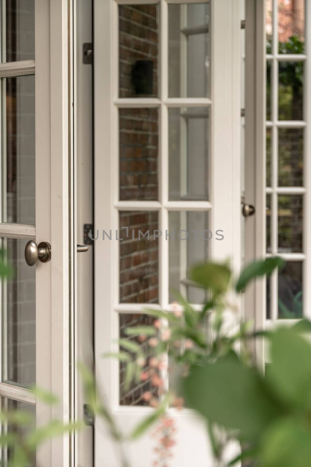 the outside of a house with some plants in front of it and an open door on the other side of the building