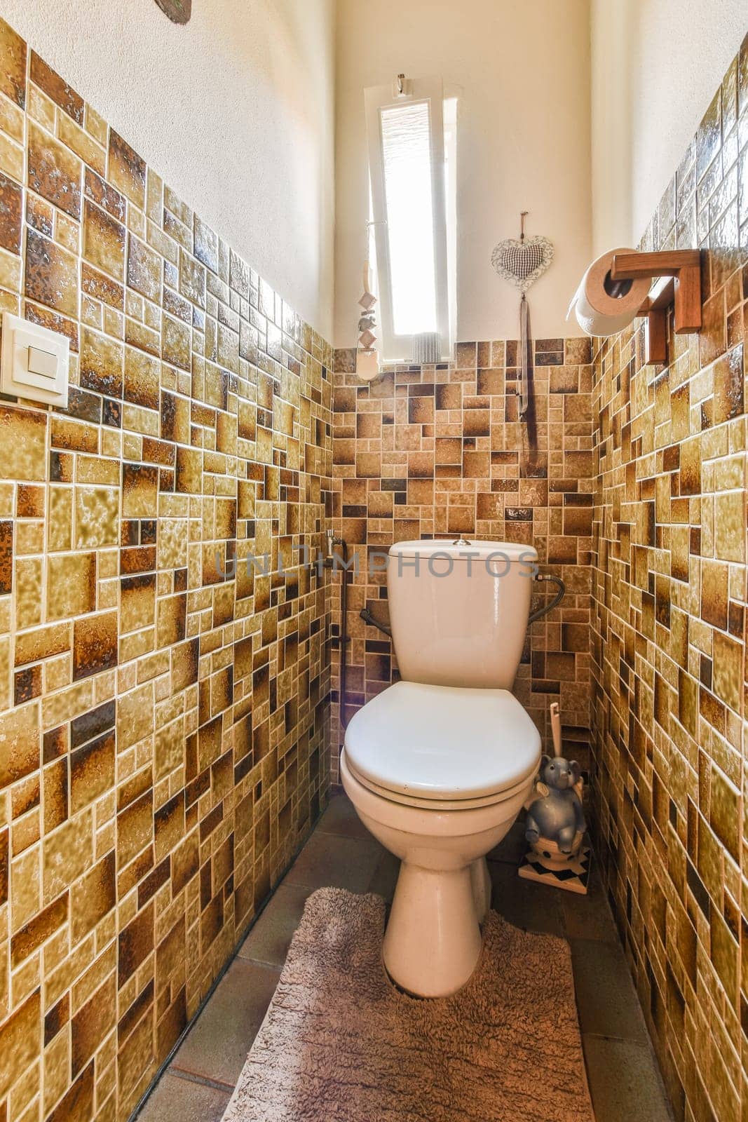 a tiled bathroom with a toilet in the middle and a rug on the floor next to the toilet is made out of tiles