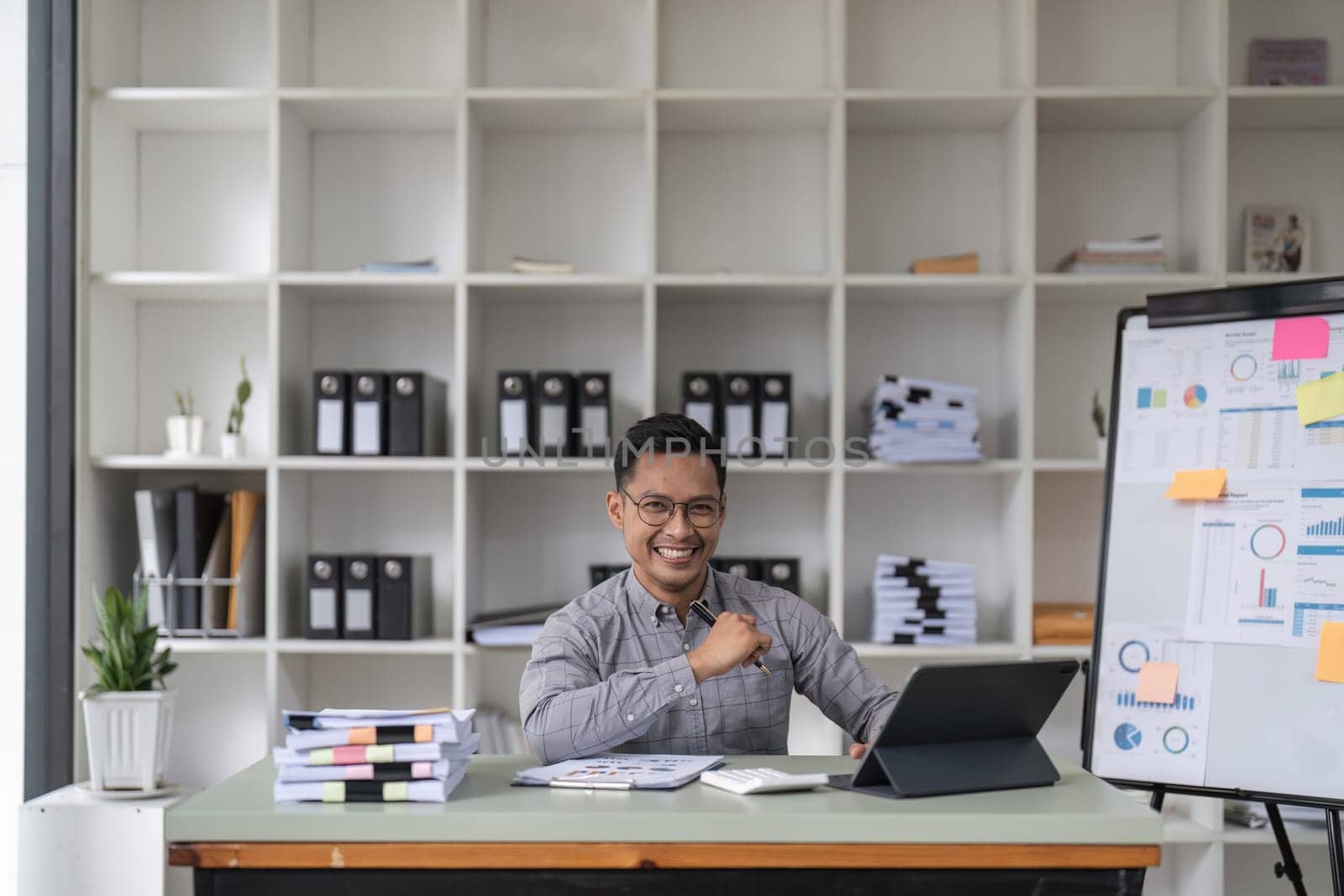 millennial office employee in glasses sitting at desk in front of laptop smiling looking at camera. Successful worker, career advance and opportunity, owner of prosperous business concept.