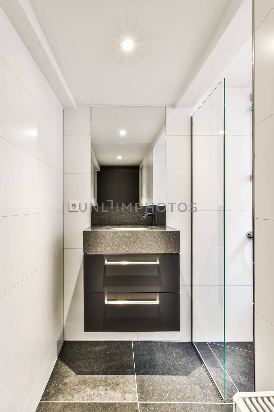 a modern bathroom with black and white tiles on the floor, shower stall and toilet in the corner is illuminated by recessed lights