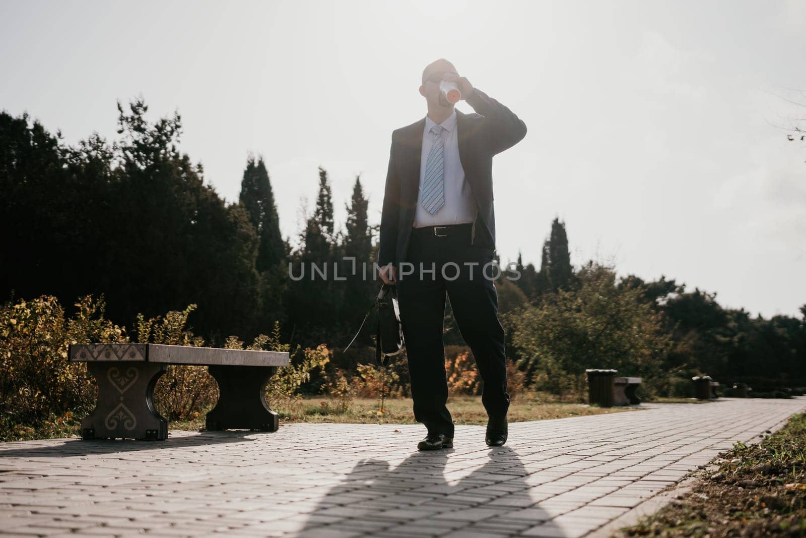 Mature entrepreneur drink coffee in autumn park. Senior executive rest in city park. by panophotograph