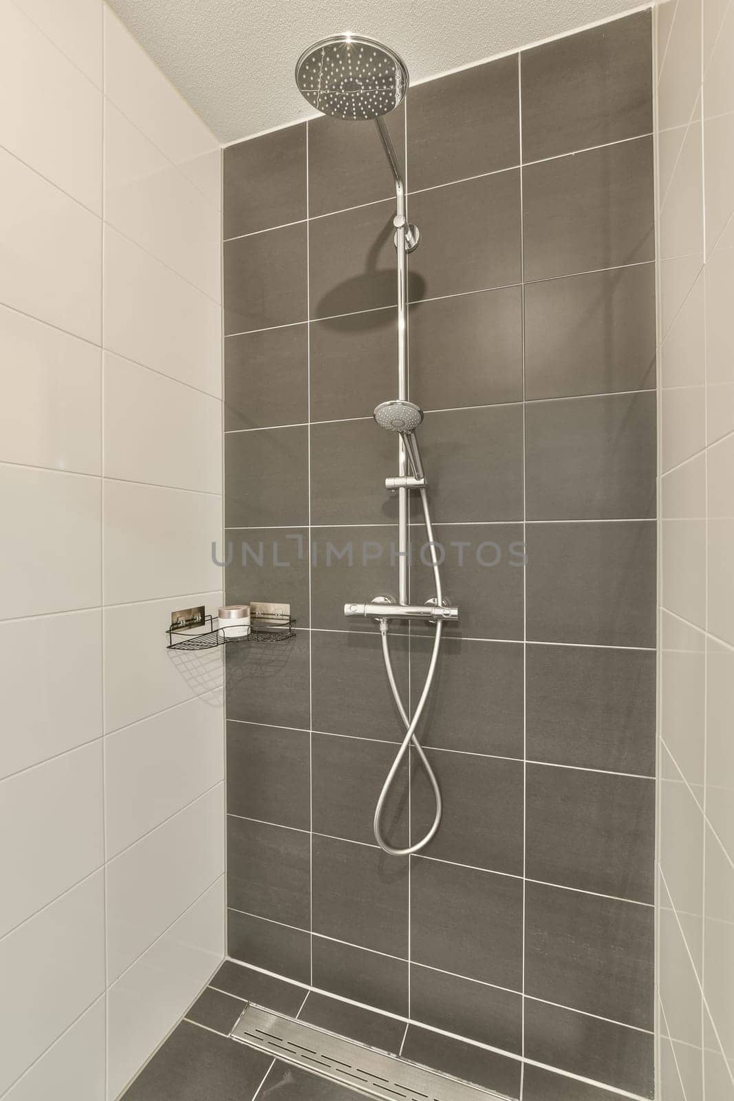 a shower with grey tiles on the wall and white trim around the tub fauced in this modern bathroom