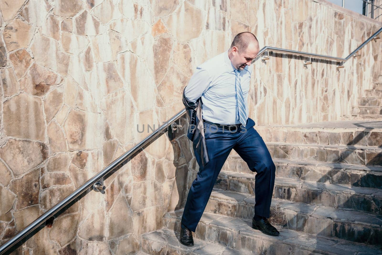 Portrait of a senior professional man in a suit with various problems. A middle-aged businessman with a briefcase descends the stairs.