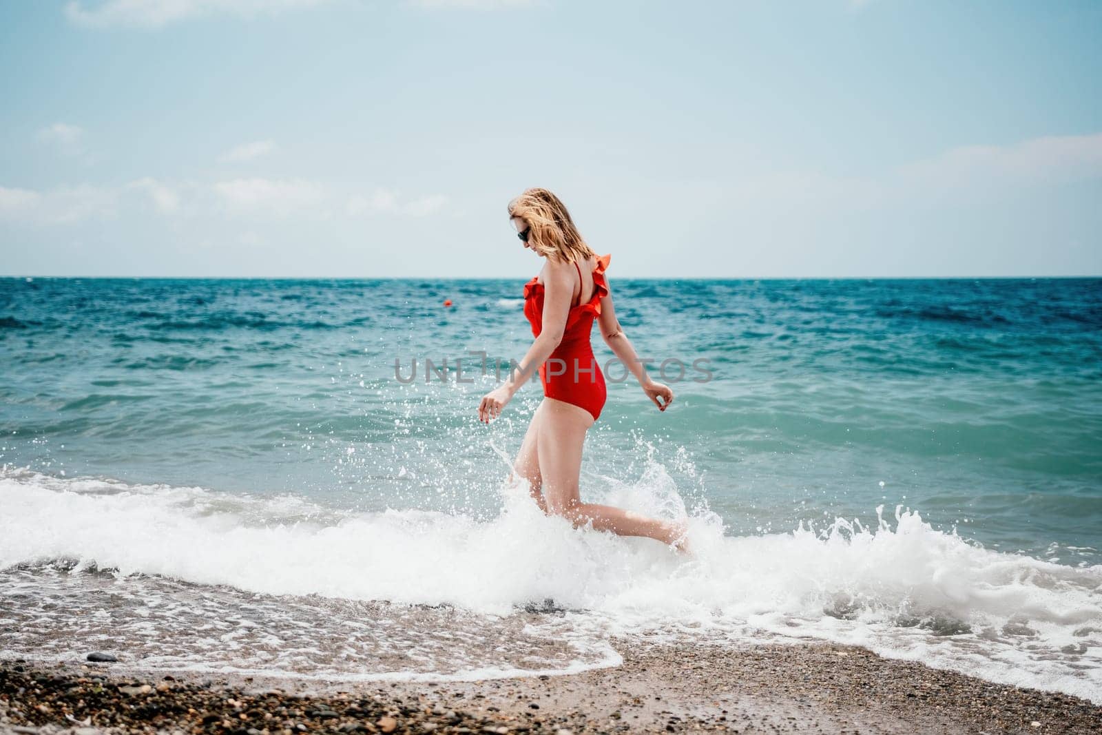 Pretty young blonde woman walking on the beach in summer, having fun, walks carefree on the seaside . Portrait beautiful young woman relax smile around beach sea ocean in holiday vacation travel trip.