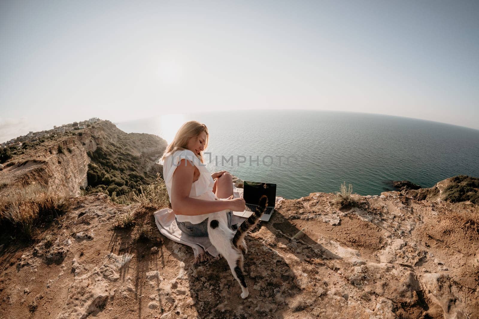 Woman sea laptop. Business woman in yellow hat working on laptop by sea. Close up on hands of pretty lady typing on computer outdoors summer day. Freelance, digital nomad, travel and holidays concept.