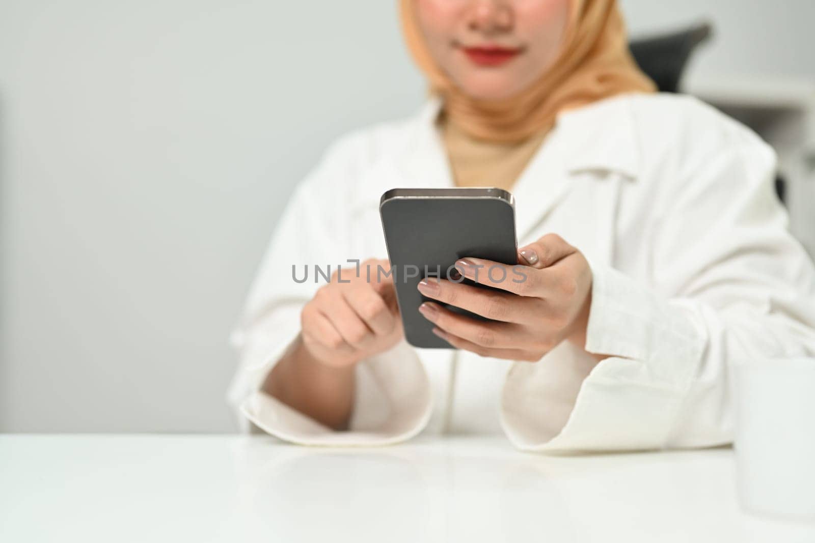 Millennial Asian muslim woman using mobile phone chatting online or communicating in social media.