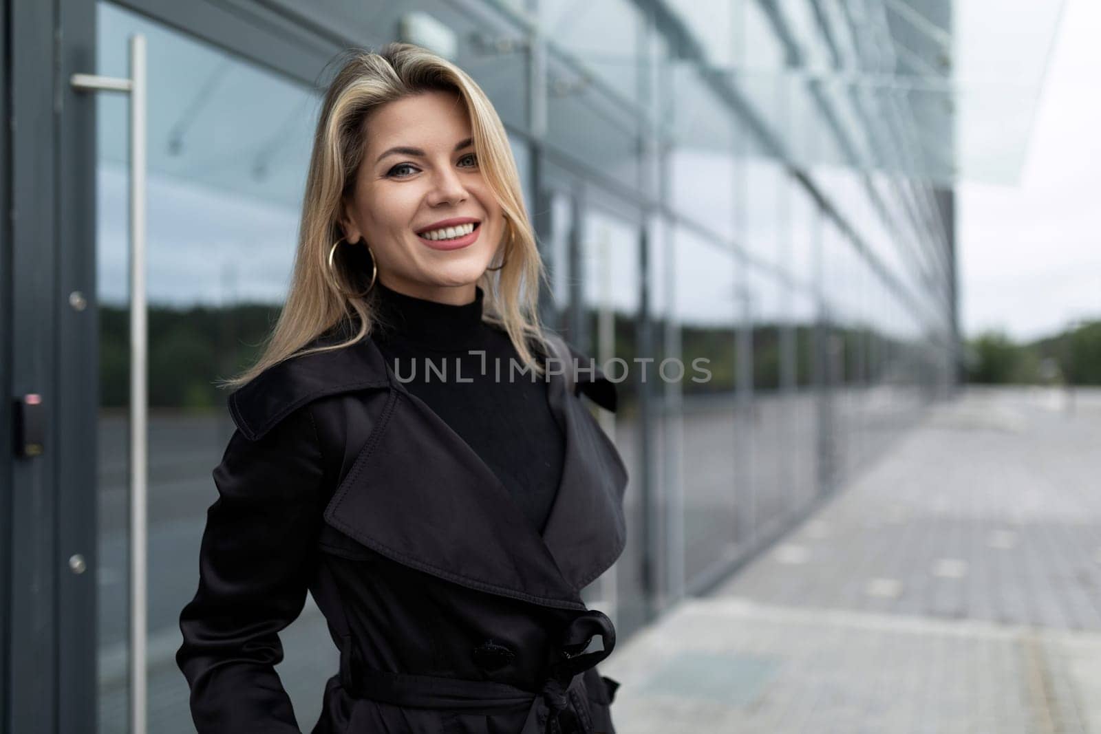 happy young woman stands confidently against the background of a modern building by TRMK
