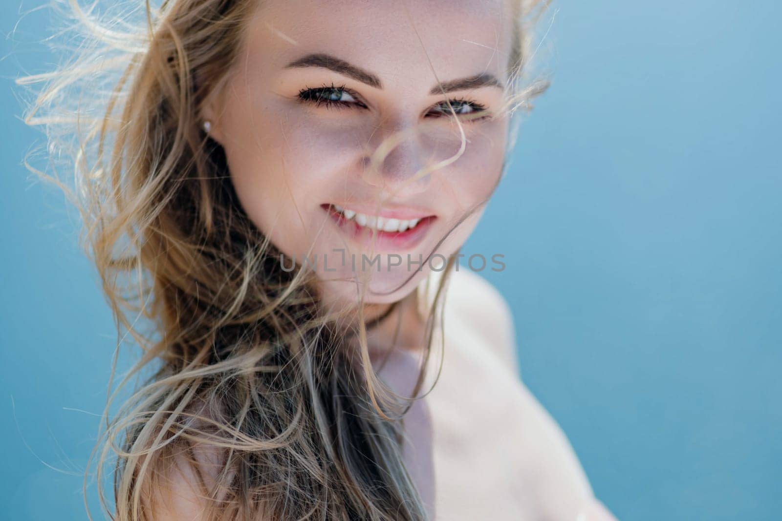 Portrait of a blond woman at the sea, a woman makes photos for memory from a trip to the sea to show to friends