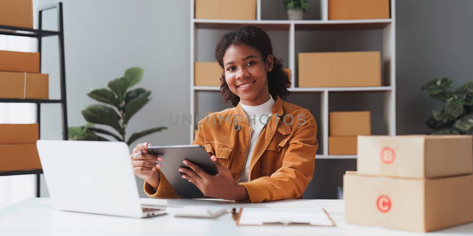 American African entrepreneur smile and use a tablet to check online order. Successful SME entrepreneur concept.