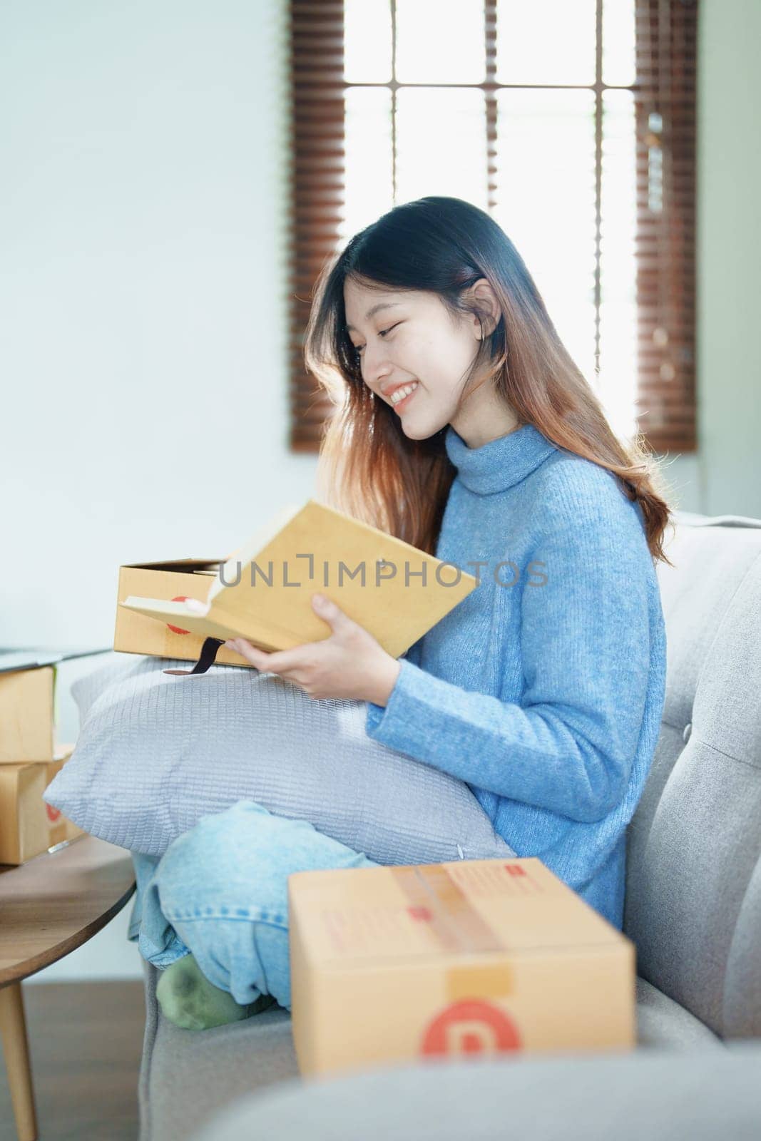 Starting small business entrepreneur of independent Asian woman smiling using computer laptop with cheerful success of online marketing package box items and SME delivery concept.