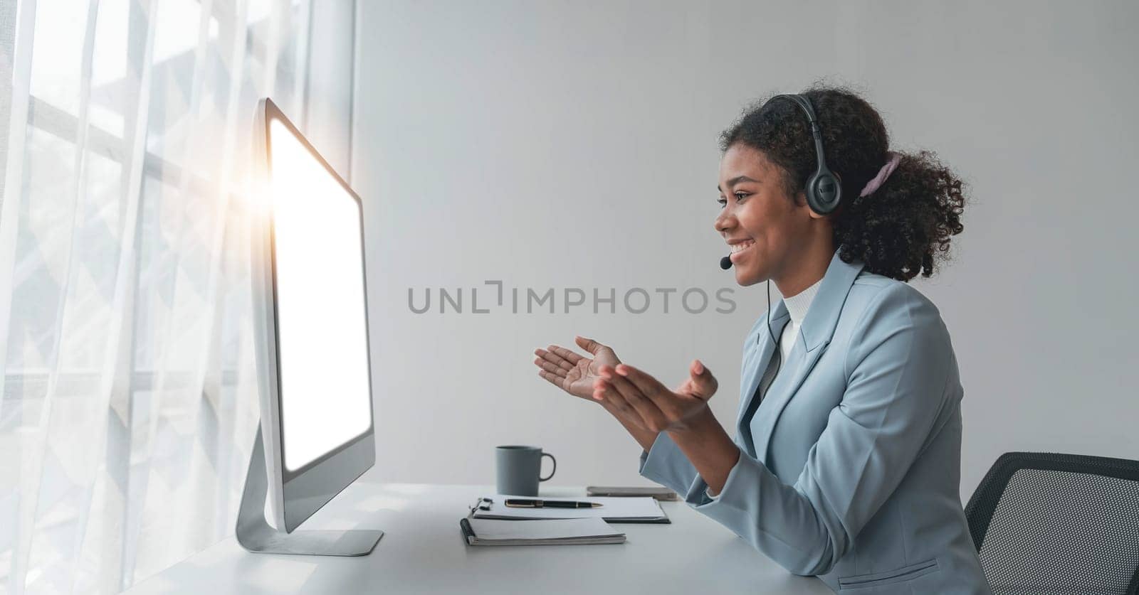 close up call center operator in wireless headset talking with customer, woman in headphones with microphone consulting client on phone in customer support service, looking at computer screen by wichayada