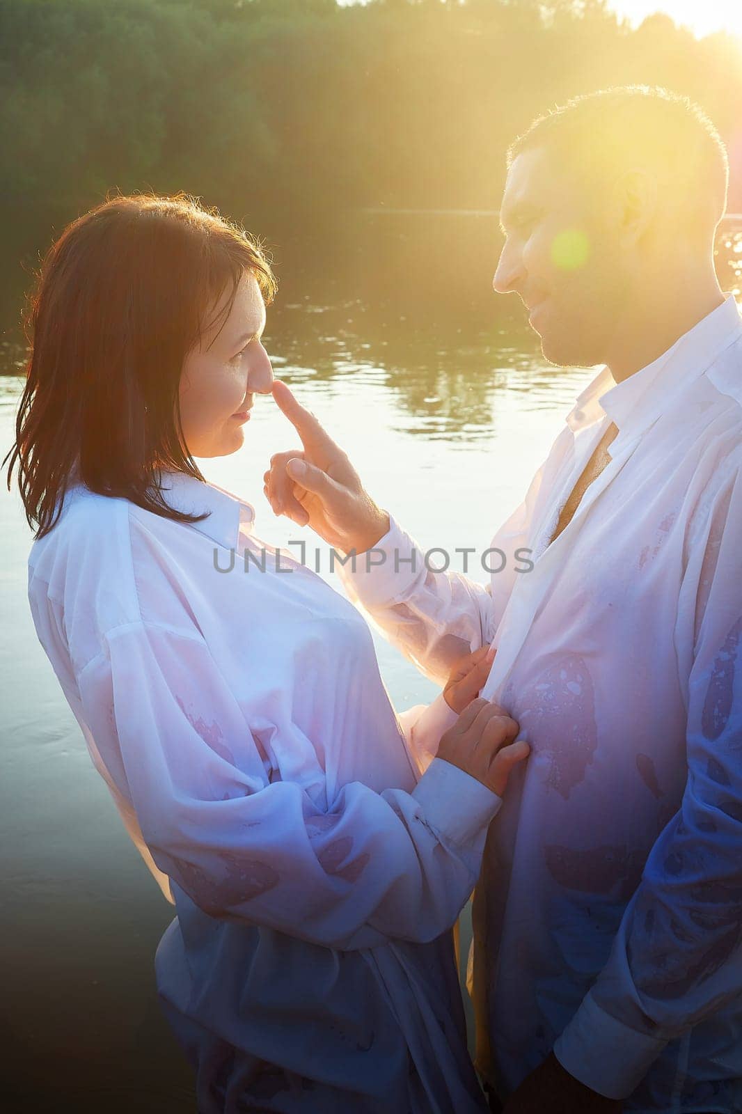Happy Couple relaxin, having fun and hugs on nature near water of river or lake in summer sunny evening during sunset. Family or lovers have date and rest outdoors. Concept of love and friendship by keleny