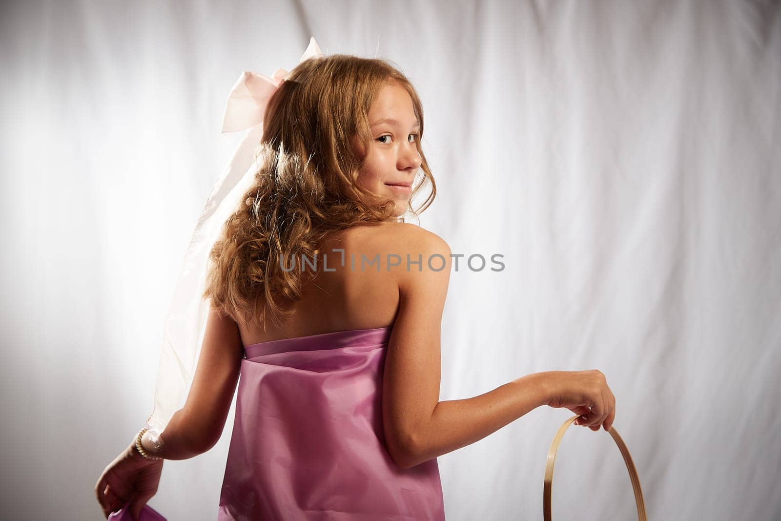 Portrait of cute kid girl posing in pink beautiful dress on white background. Model in studio looking as gentle magic princess from fairy taly having photo shoot on white background