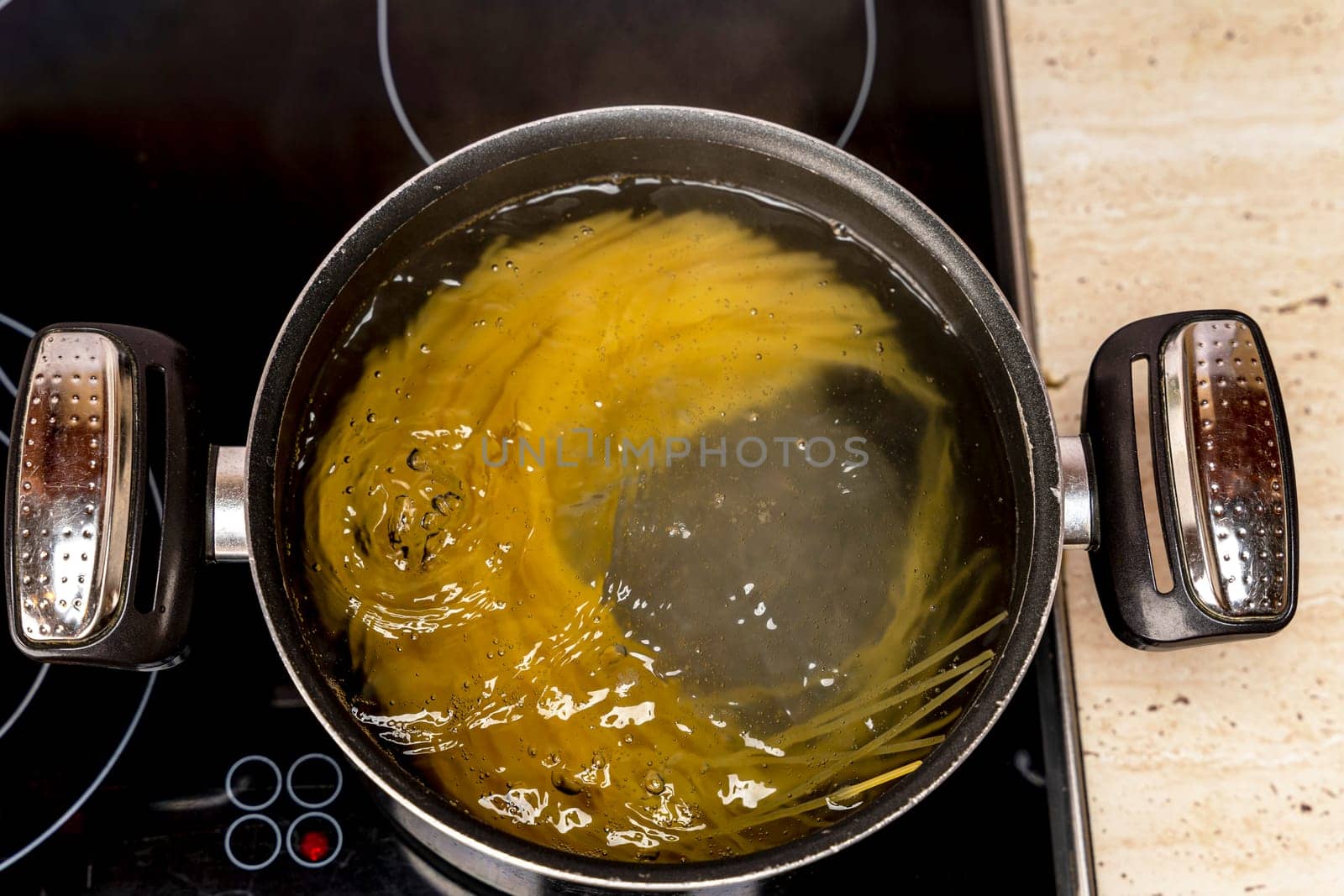 Spaghetti is cooked in a saucepan. Cooking delicious spaghetti in boiling water. pasta in a saucepan on the stove. top view