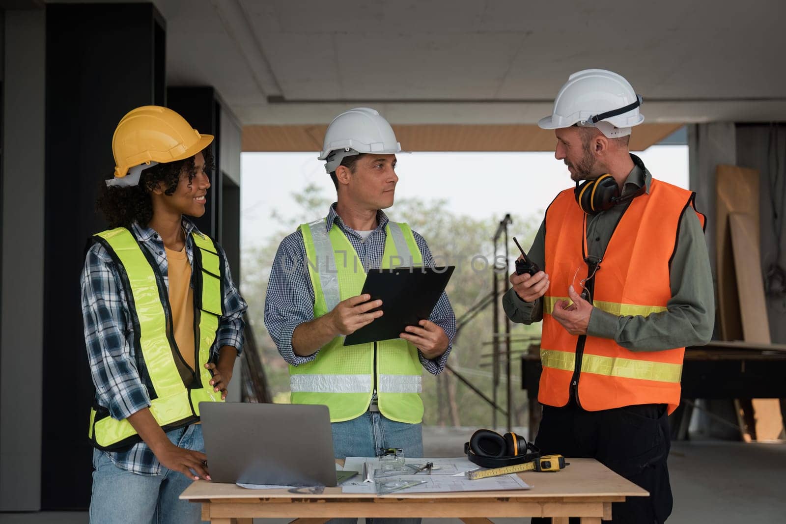 Architect team working with blueprints for architectural plan, engineer sketching a construction project on table in working site.