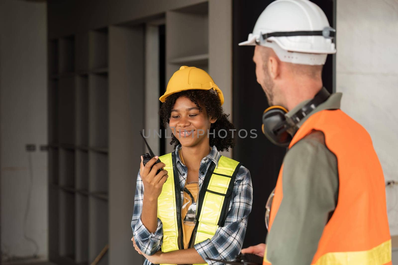 Female male engineers holding walkie talkie radios and inspecting construction site.