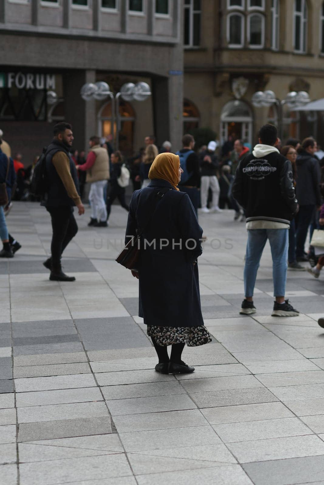 Vertical shot of a woman wearing a hijab standing in front of Cologne Cathedral, Cologne, Germany