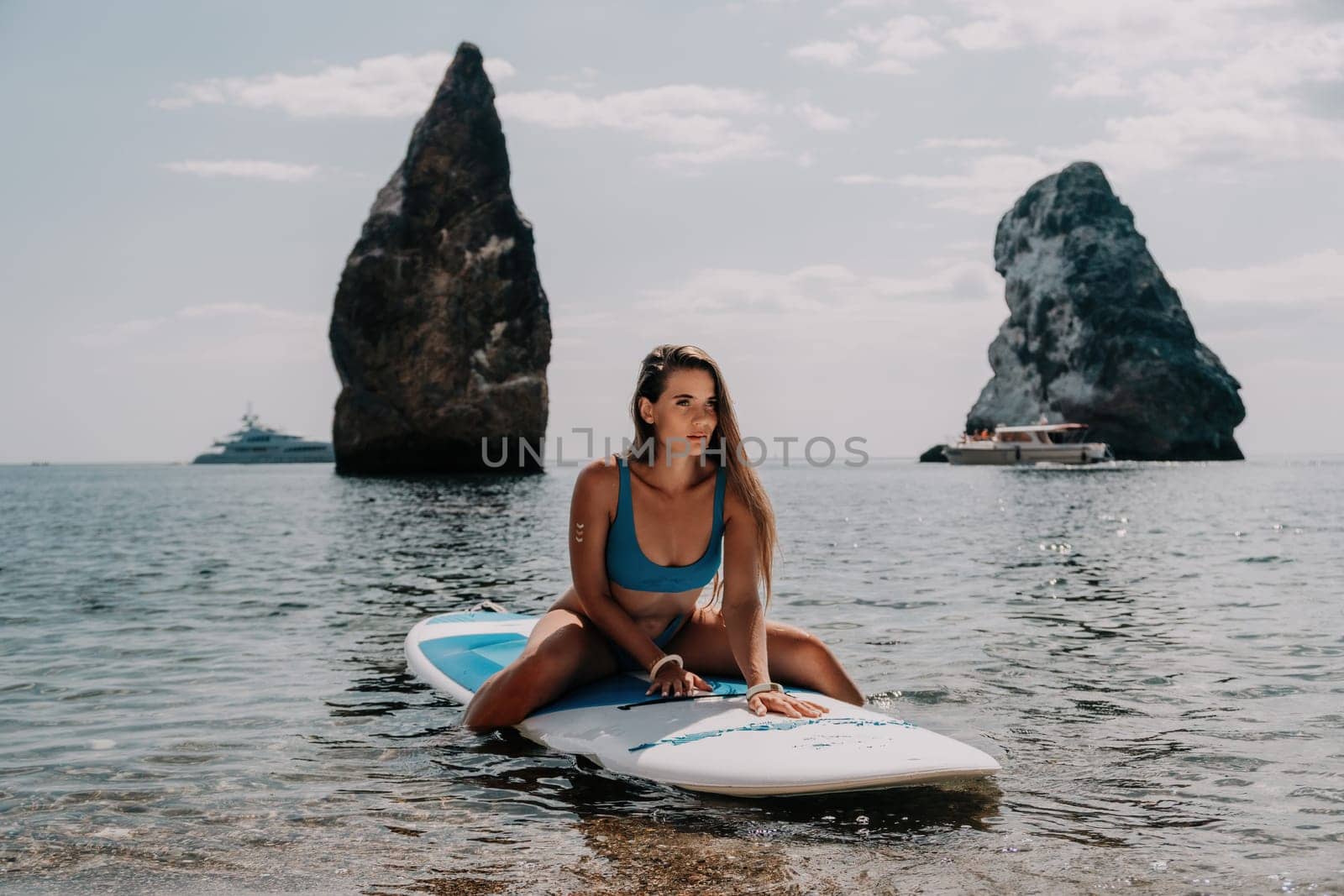 Woman sea sup. Close up portrait of happy young caucasian woman with long hair looking at camera and smiling. Cute woman portrait in bikini posing on sup board in the sea by panophotograph