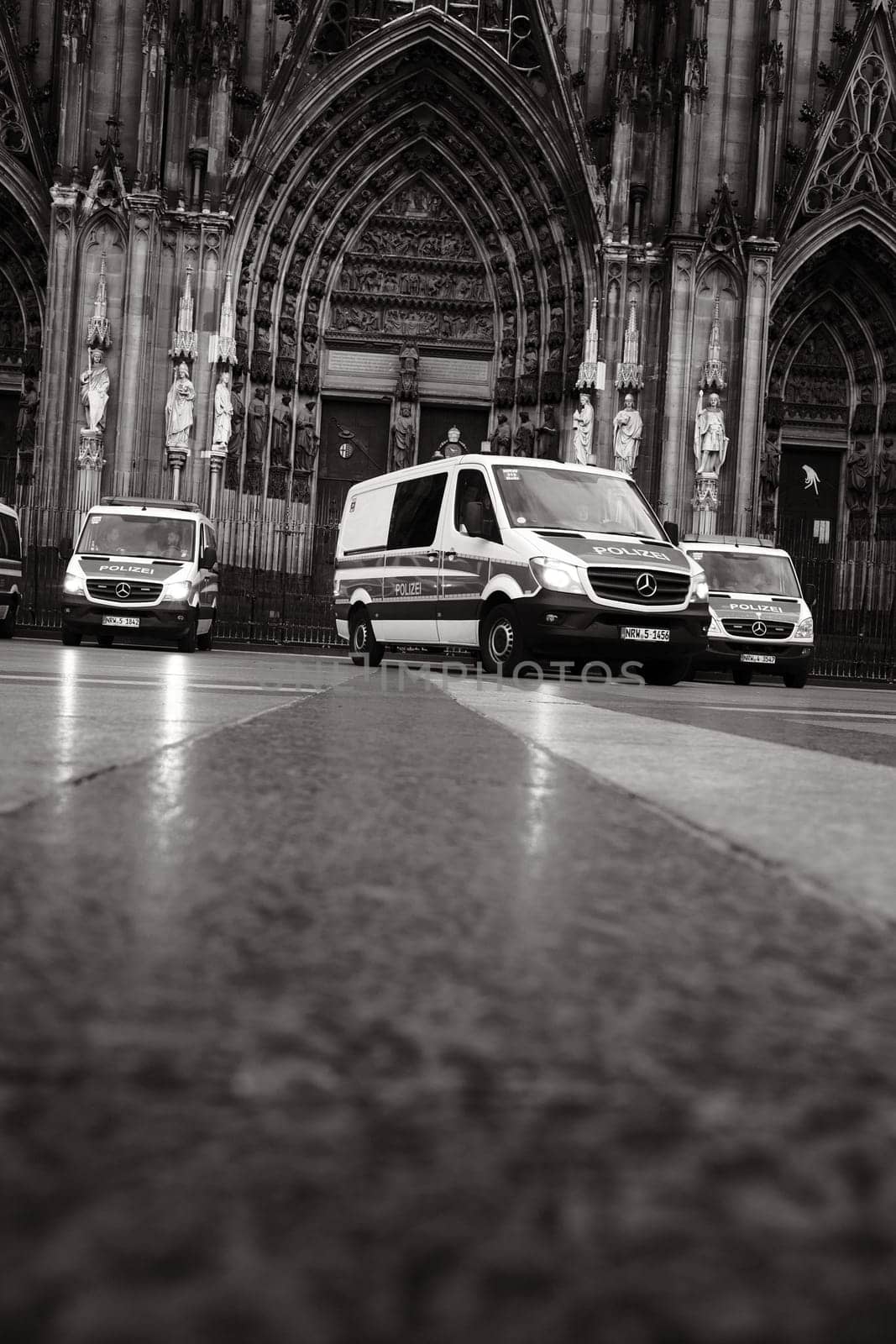 Grayscale shot of many Mercedes-Benz Sprinter police cars in front of Cologne Cathedral in Germany