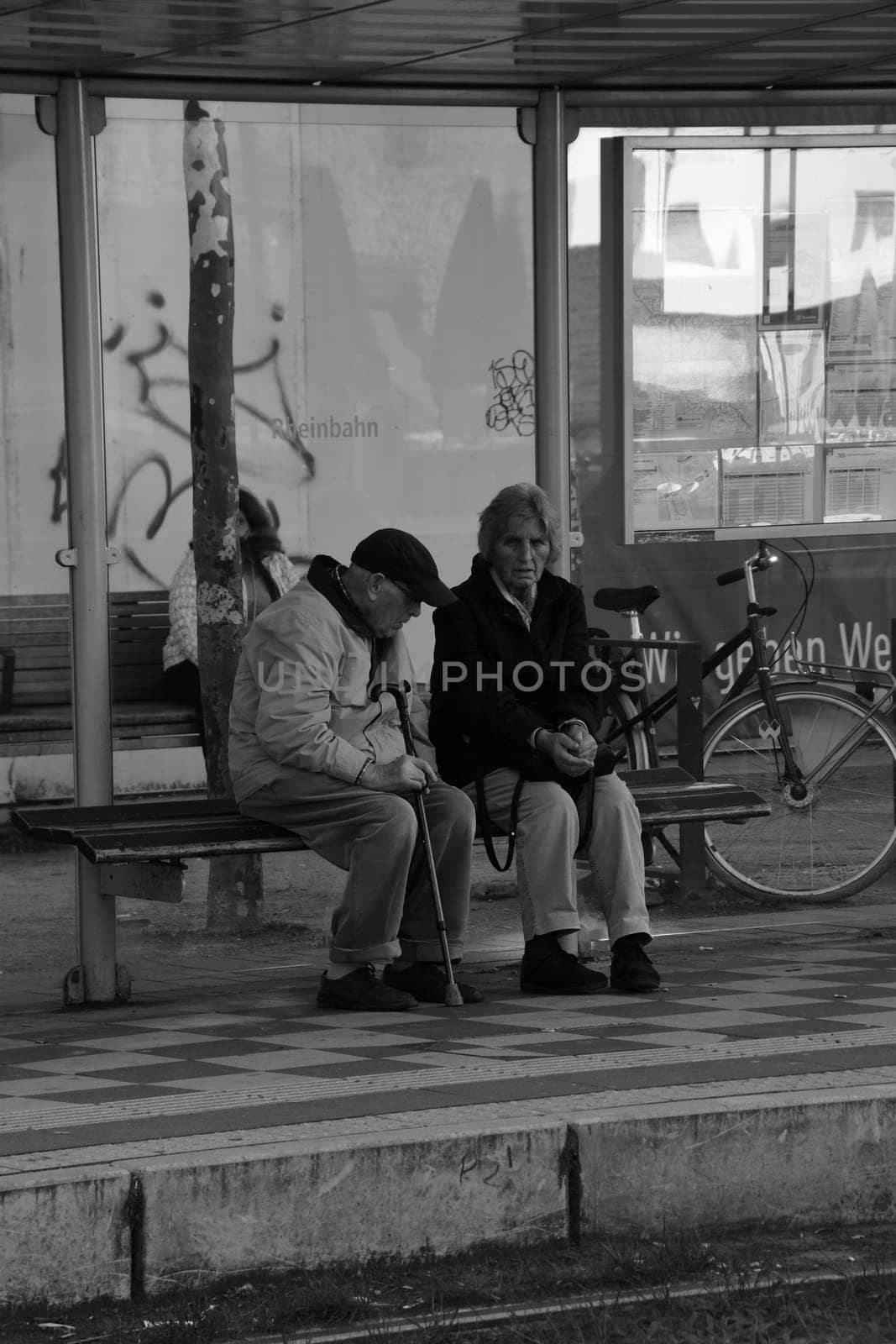Elder pensioner couple waiting at bus stop in Dusseldorf, Germany