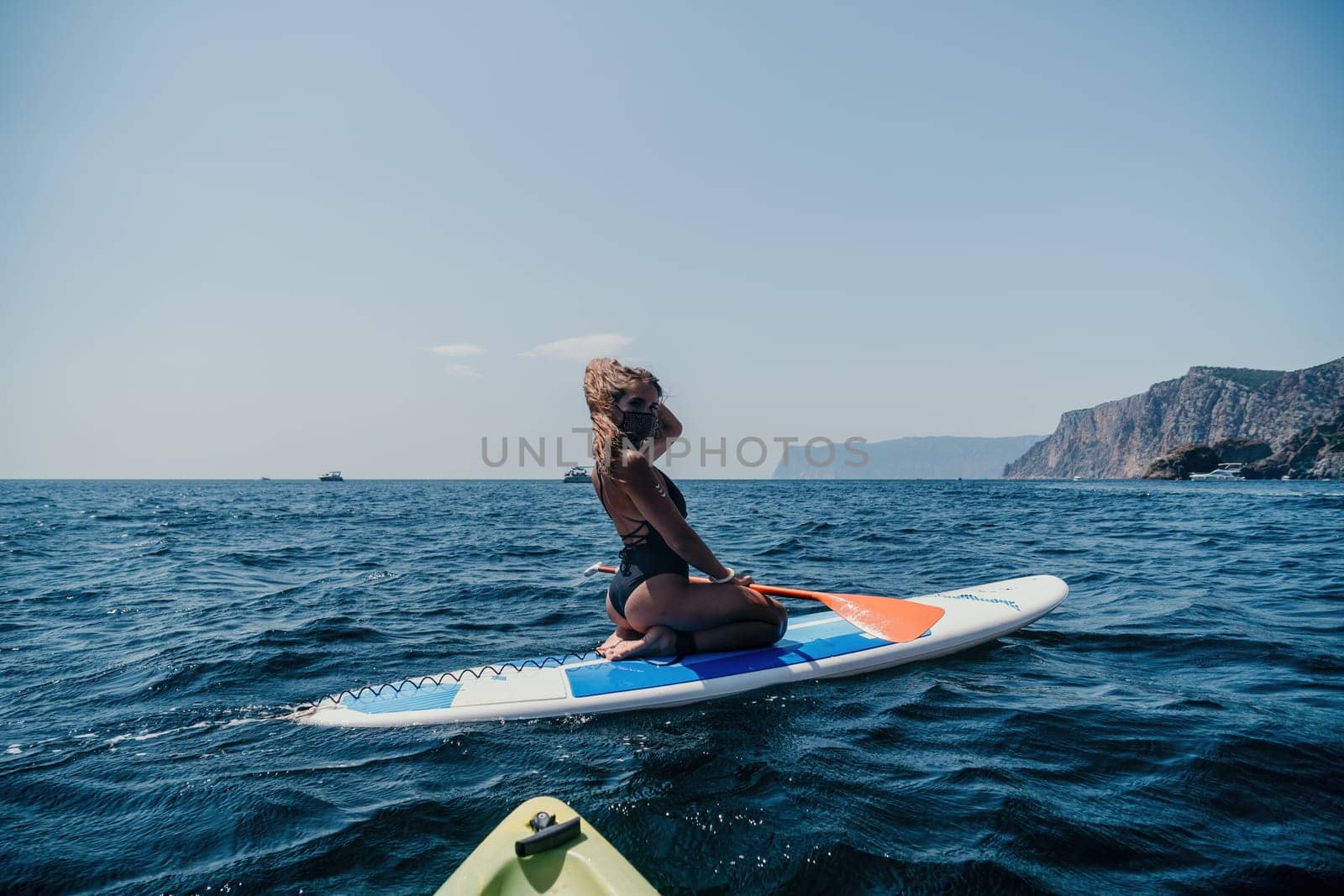 Woman sea sup. Close up portrait of happy young caucasian woman with long hair looking at camera and smiling. Cute woman portrait in bikini posing on sup board in the sea by panophotograph