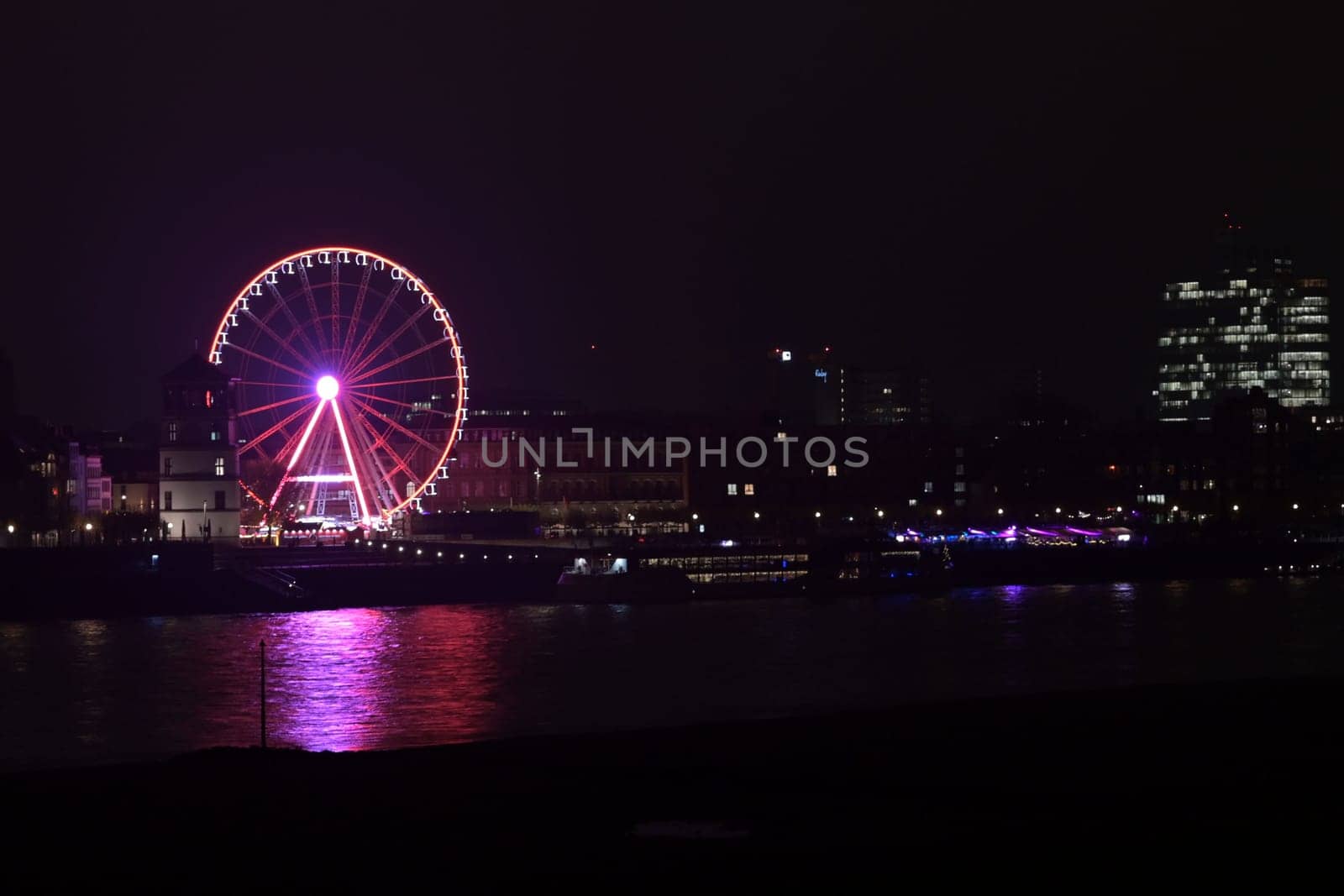 Rhine riverbank by night with castle tower and Ferris pink wheel in Duesseldorf, Germany