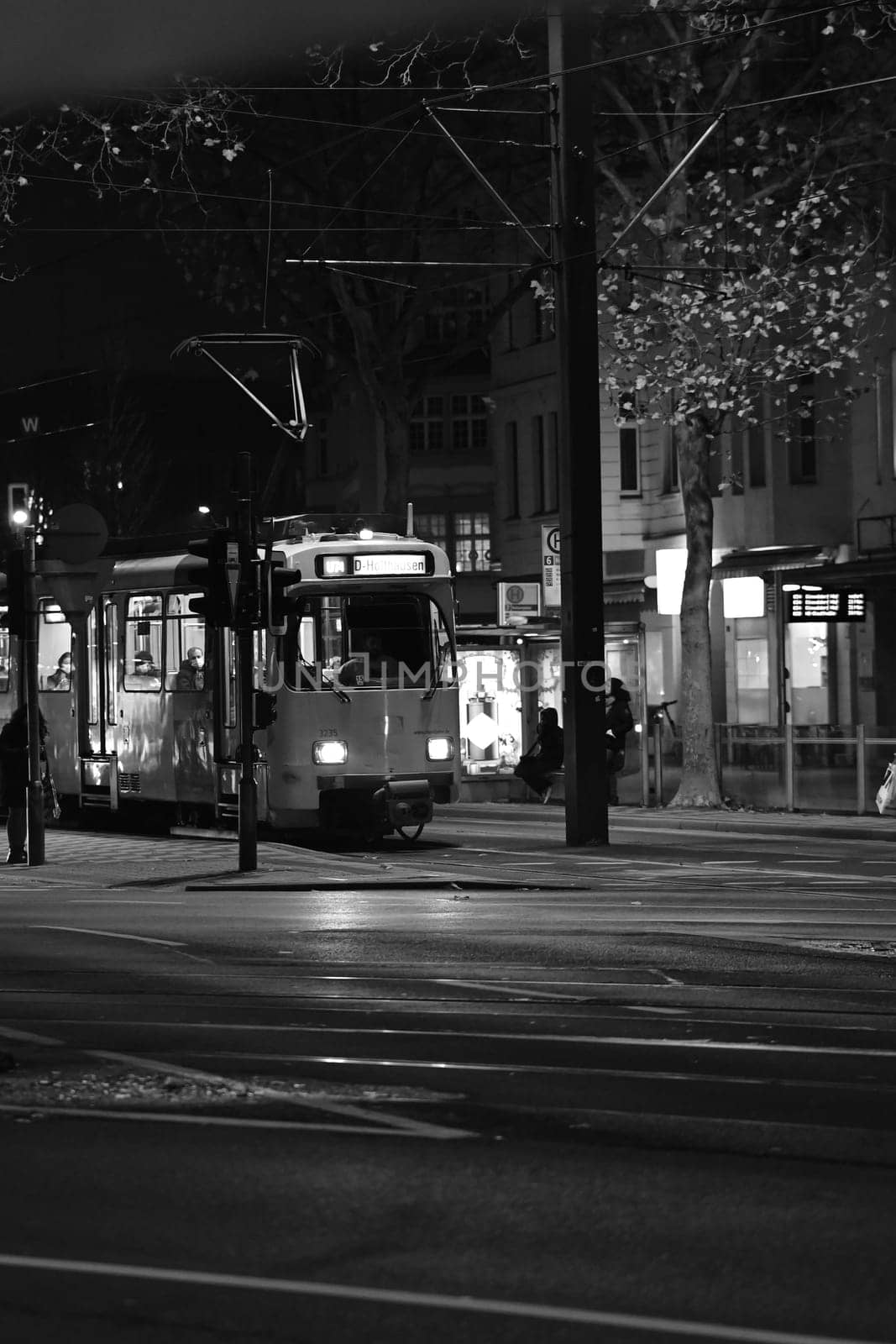 Grayscale of a tram going through town streets at night on the street