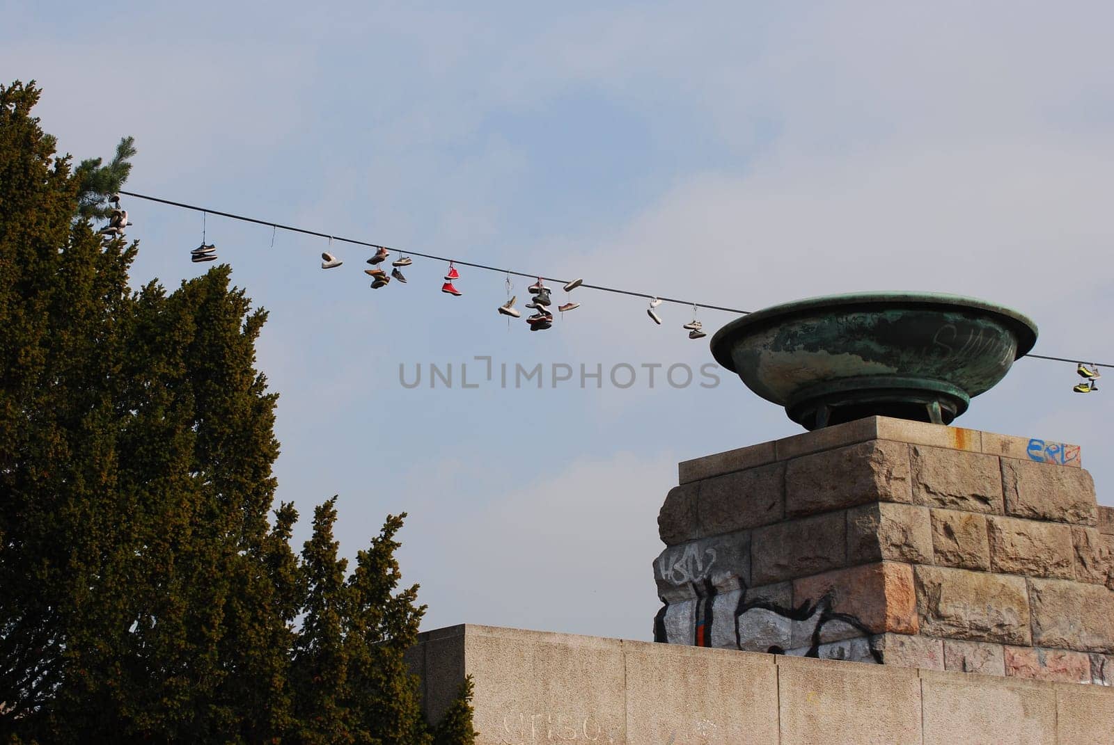 Low-angle shot of shoes hanging on a rope leash with a cloudscape in the background