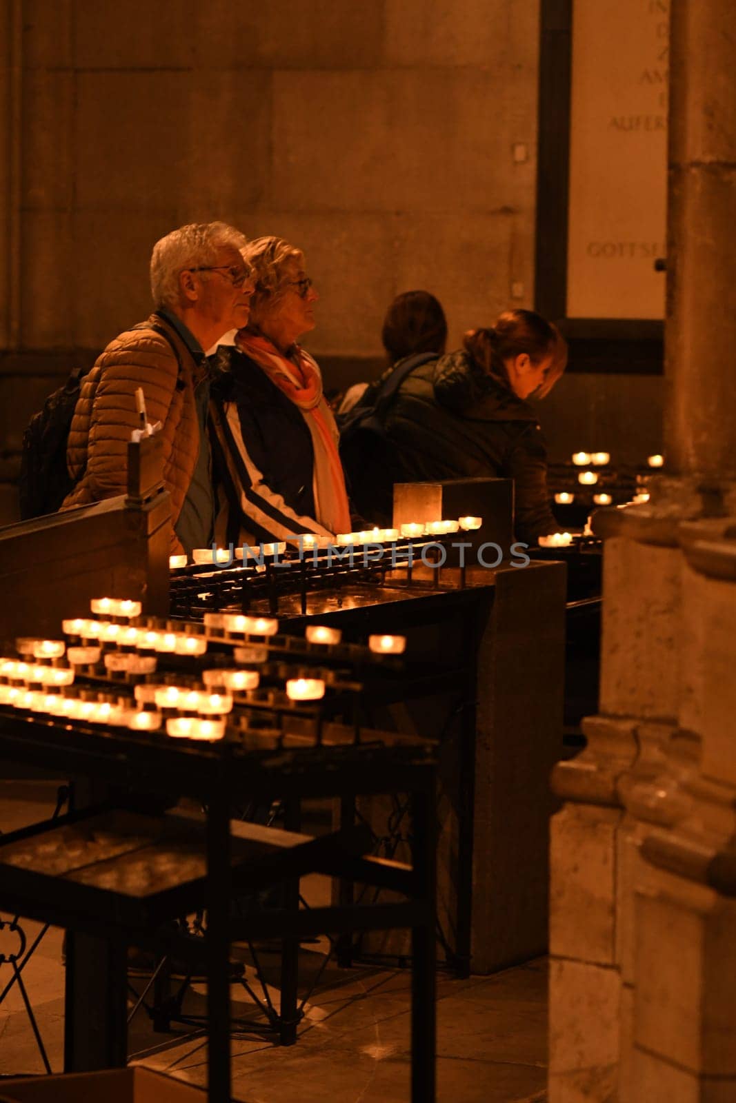 People hold devotions in front of a sea of candles at Cologne Cathedral in Cologne, Germany