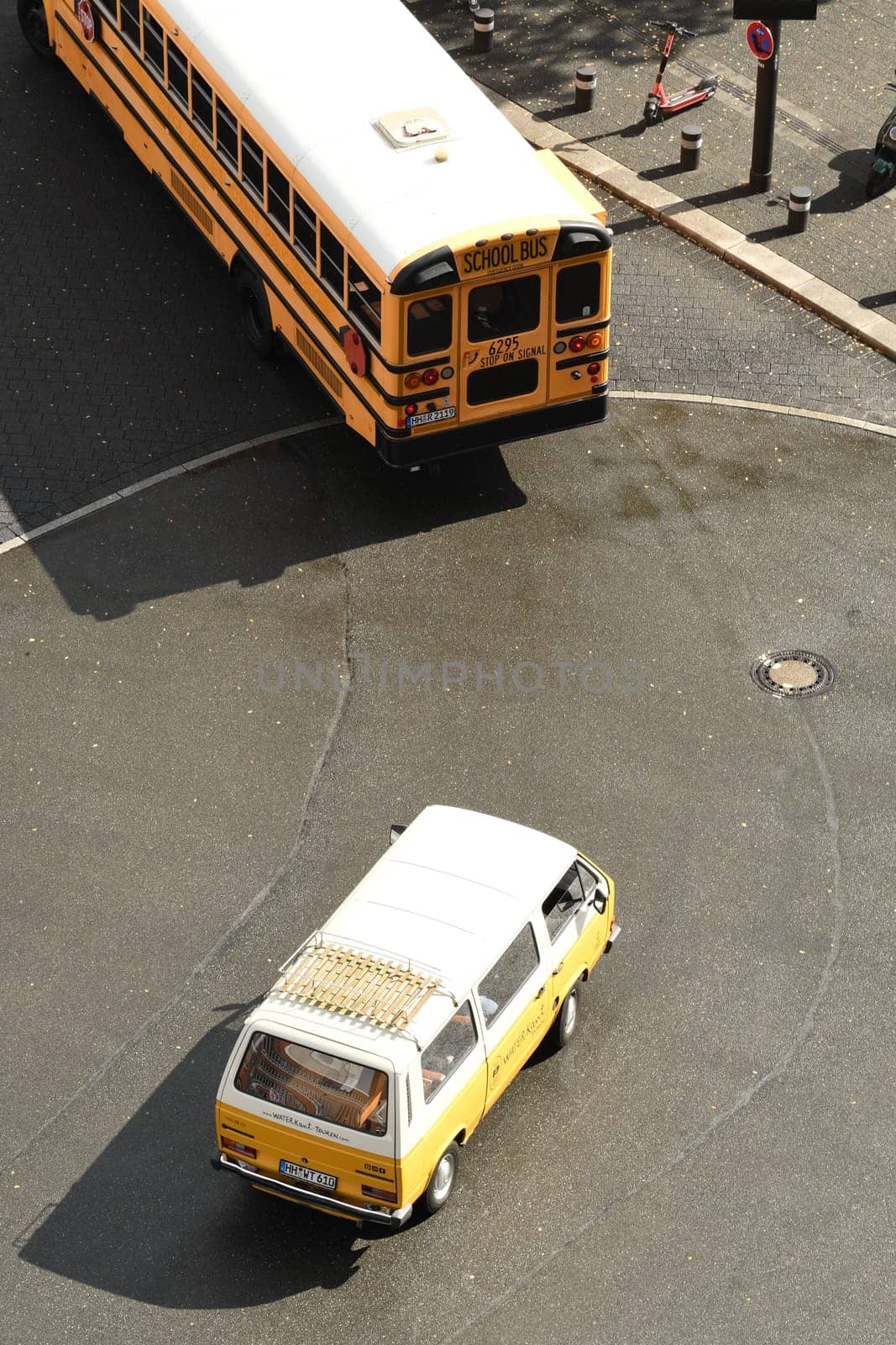 Vertical shot of a yellow and white automobile driving behind an American school bus on a roadway