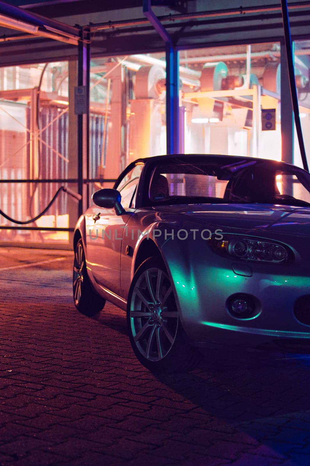 Silver JDM convertible at night in front of a car wash and neon lights