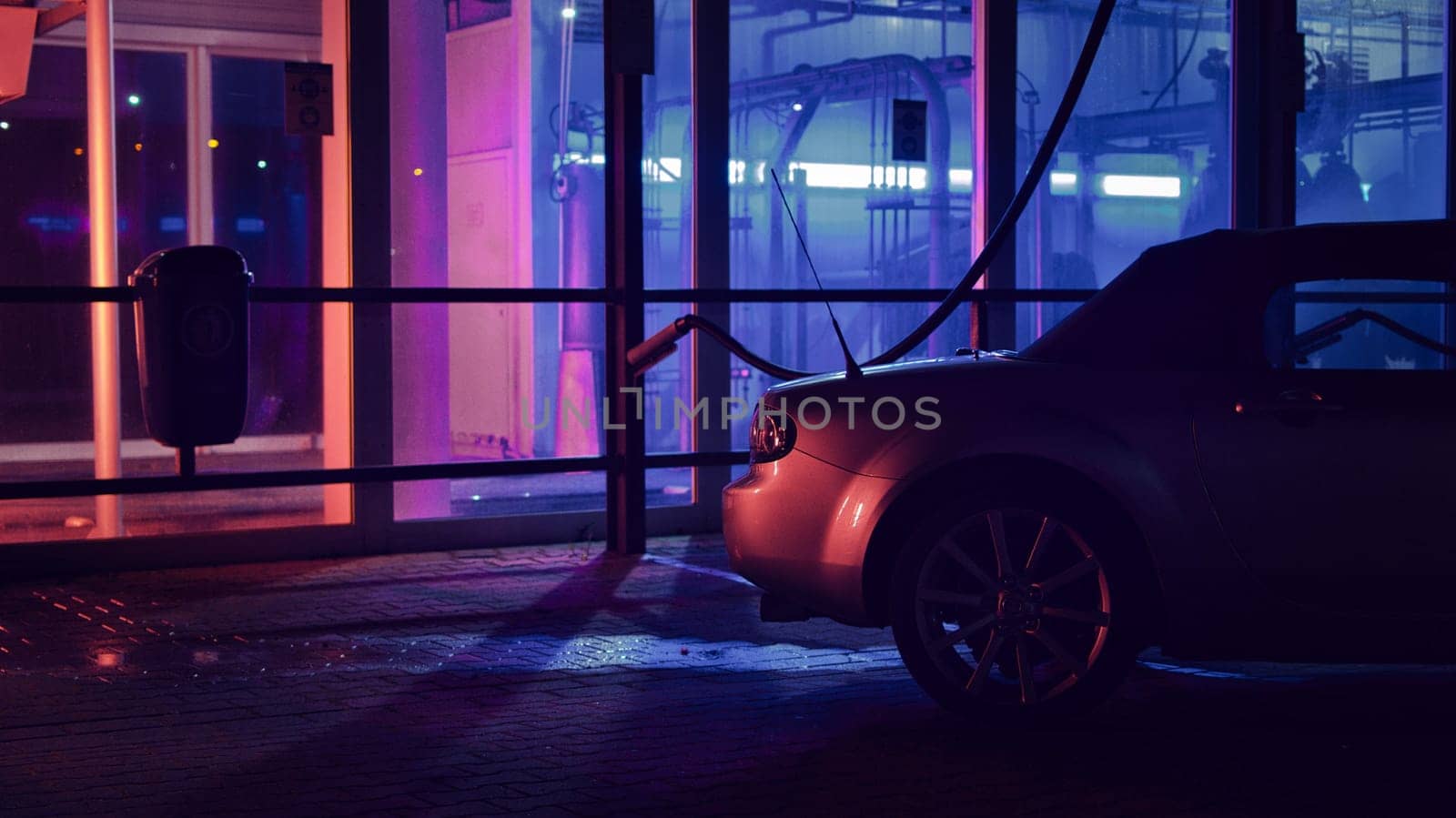 Silver JDM convertible at night in front of a car wash and neon lights