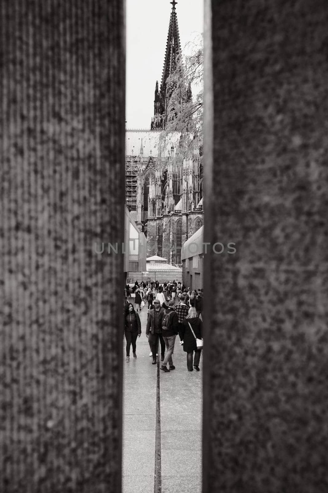 Greyscale shot of the Cologne Cathedral between two stone columns in Cologne, Germany