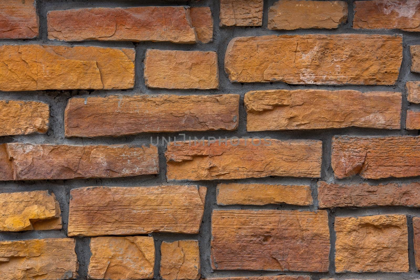 flat close-up full frame background and texture of decorative orange stone bricks.