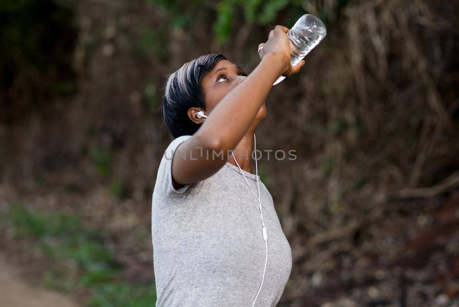 young sporty woman drinking water outdoors after fitness