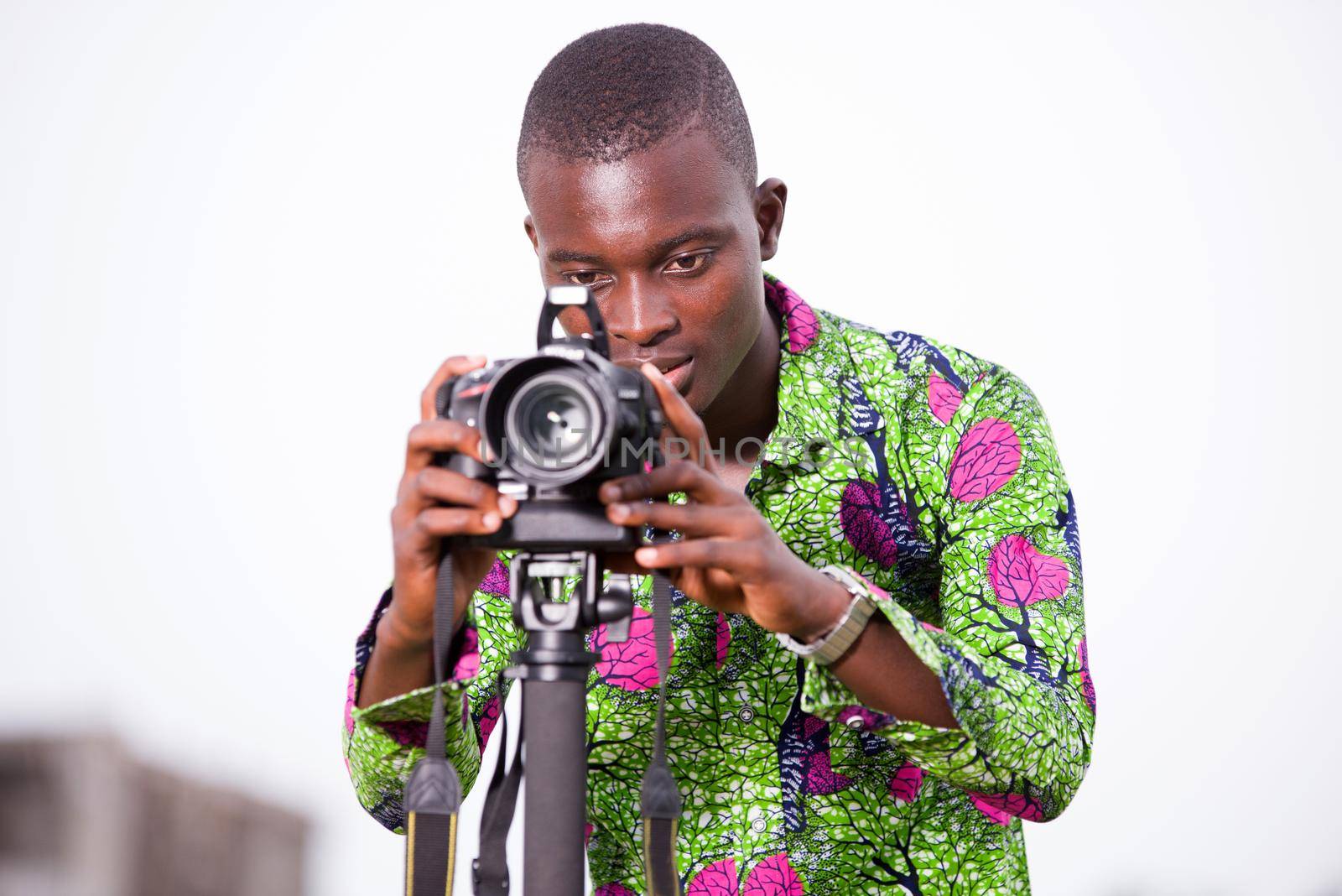 portrait of tourist photographer with professional camera. man standing behind the camera and watching his pictures taken during the day