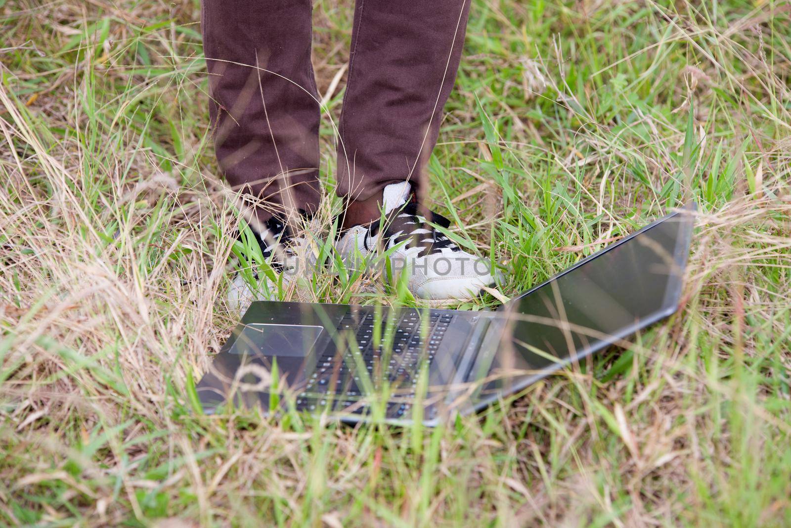 male feet and laptop in the grass.