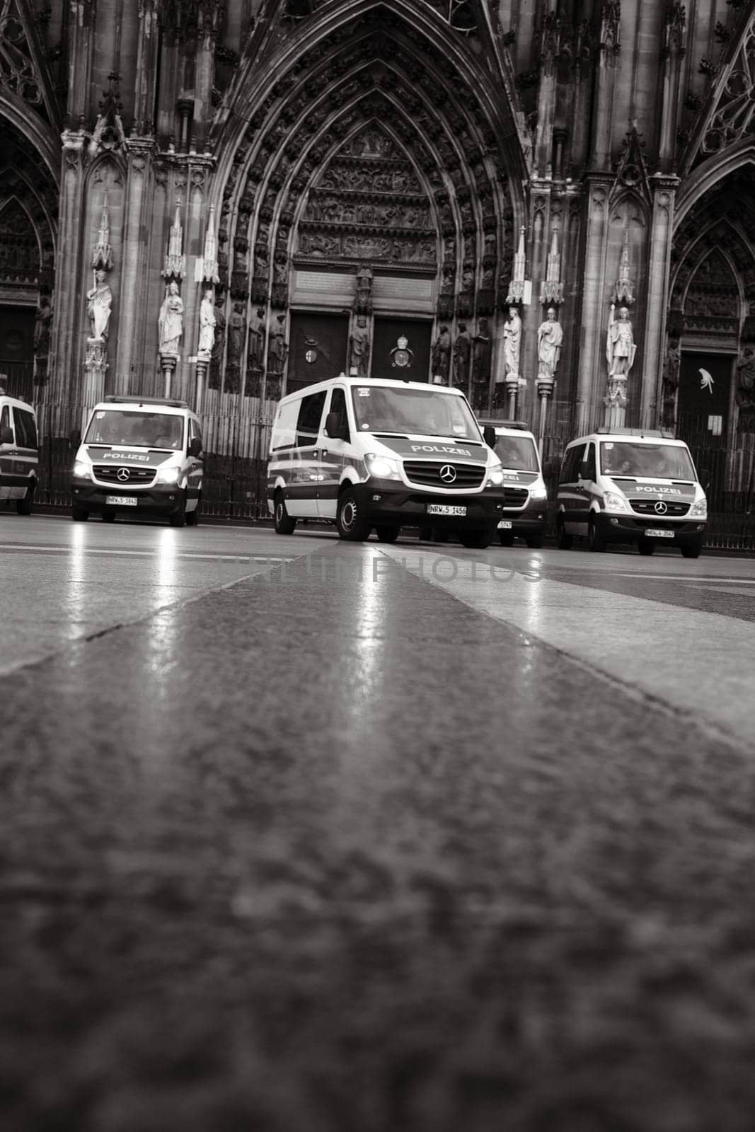 Grayscale shot of many Mercedes-Benz Sprinter police cars in front of Cologne Cathedral in Germany
