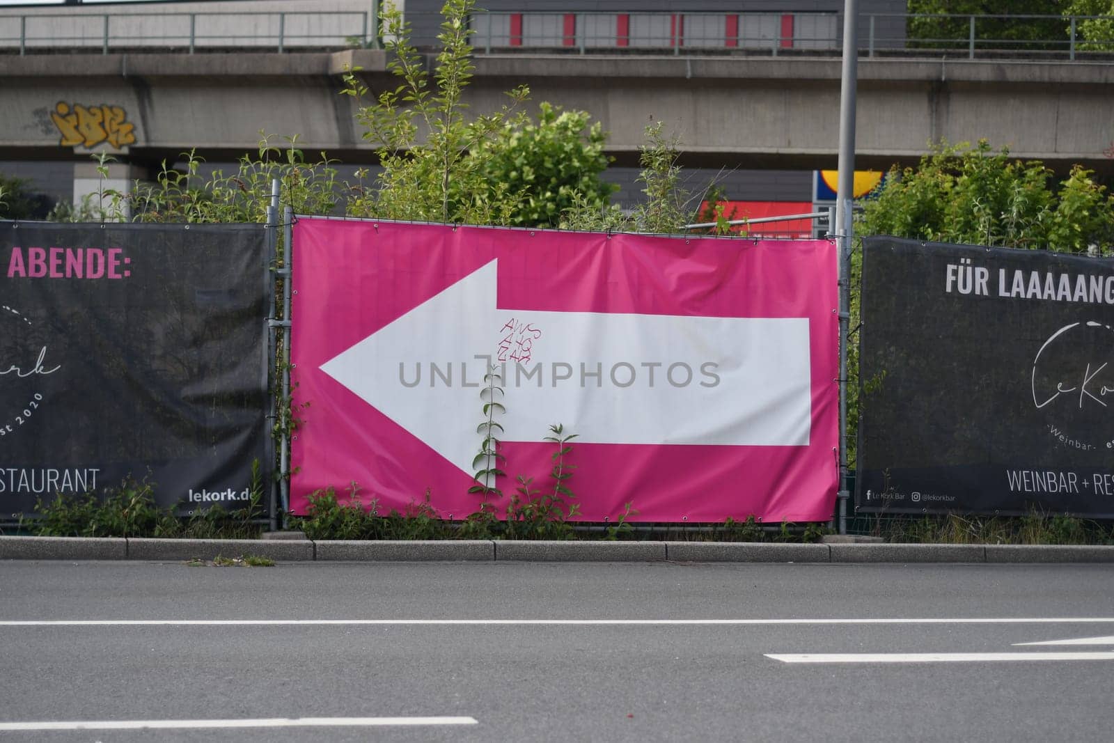 Billboard with a pink poster and a white arrow pointing left