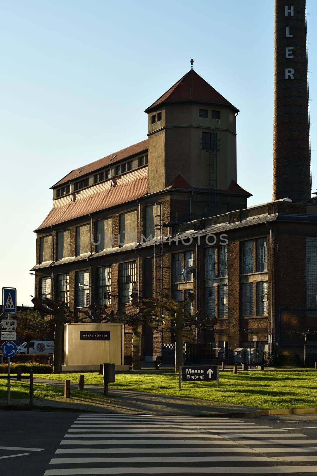 Vertical shot of a historical company building with a tower and chimney on the Areal Boehler site