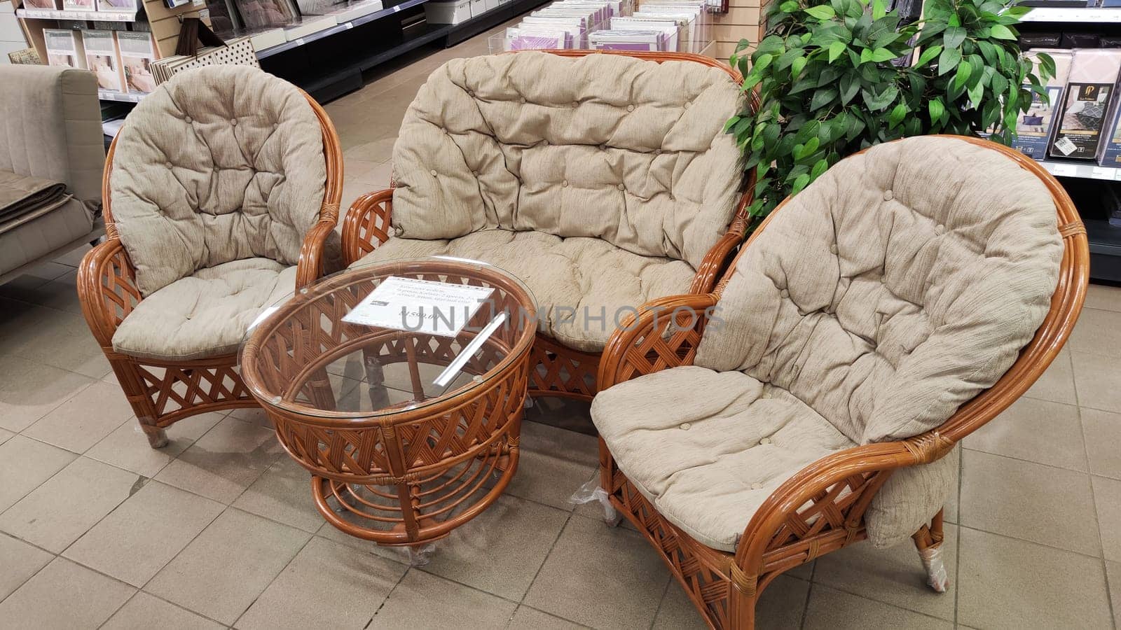 Kirov, Russia - February 18, 2023: Set of garden furniture from rattan with soft pillows on hall of shop. Background and location for photo shoots by keleny