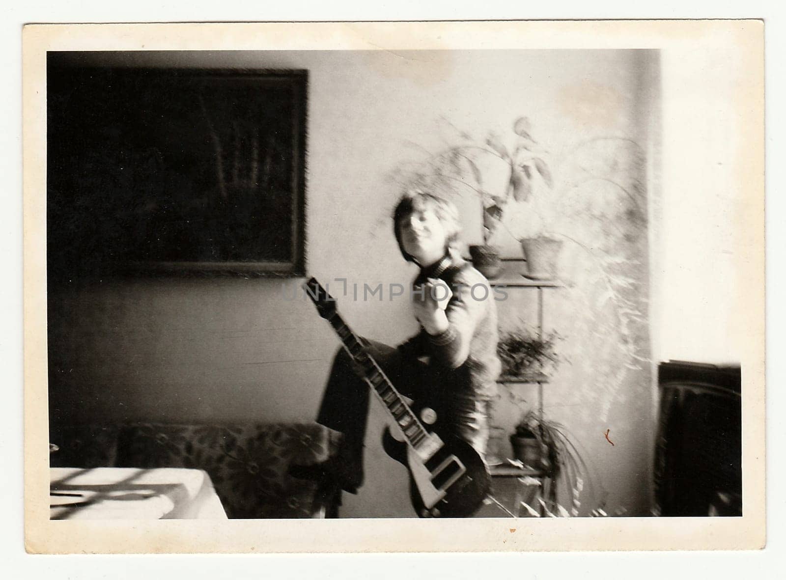 Vintage photo shows a young boy plays on the guitar. Photo has blurryness. by roman_nerud