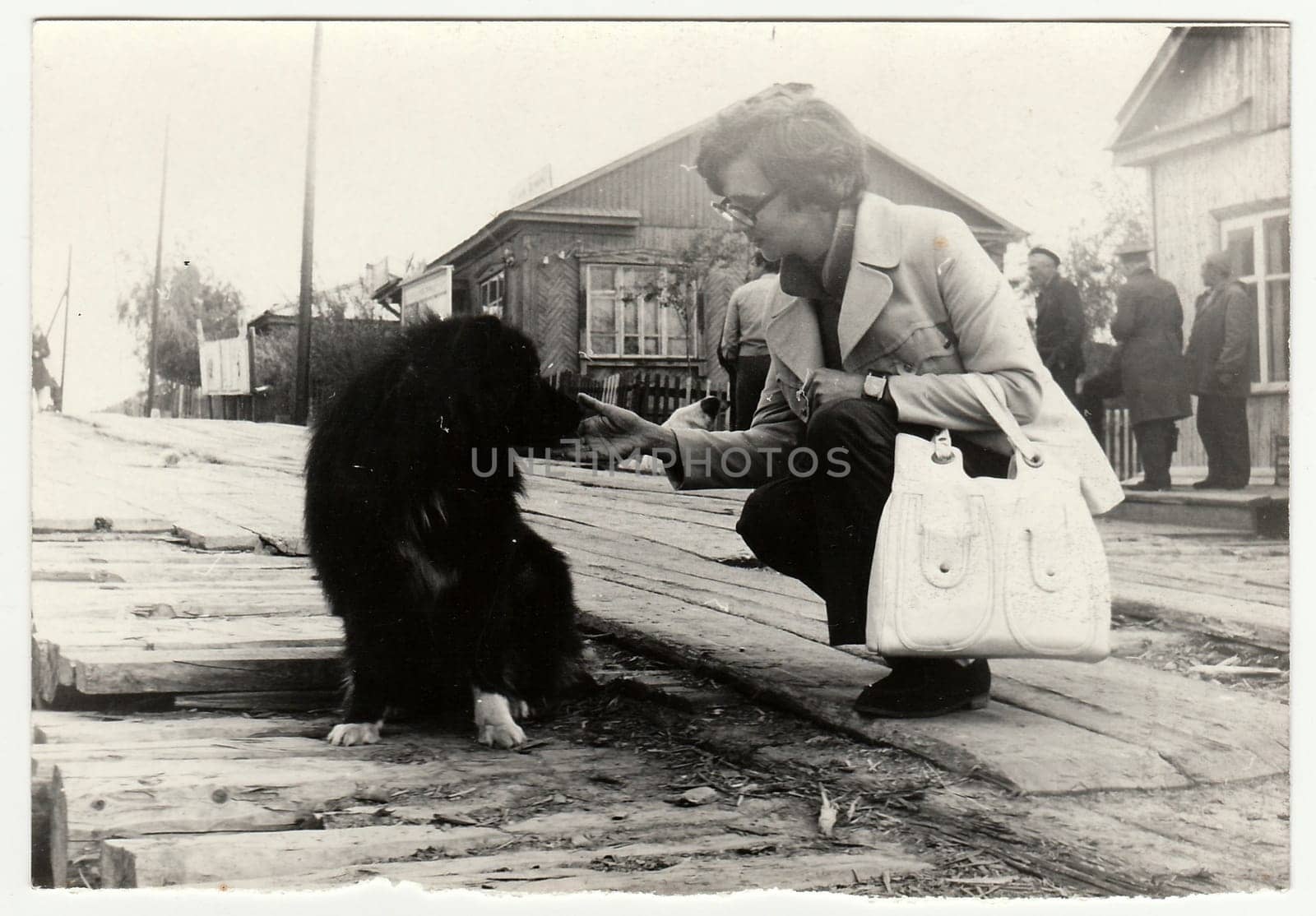 Vintage photo shows woman strokes the dog on the street. by roman_nerud