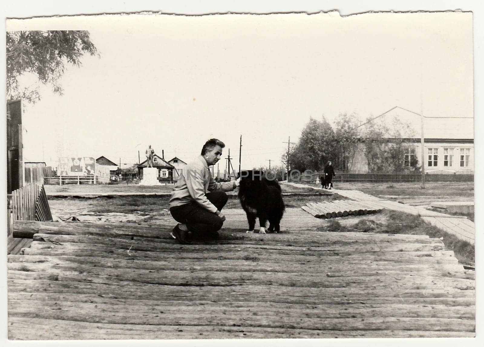 Vintage photo shows man strokes the dog on the street. by roman_nerud