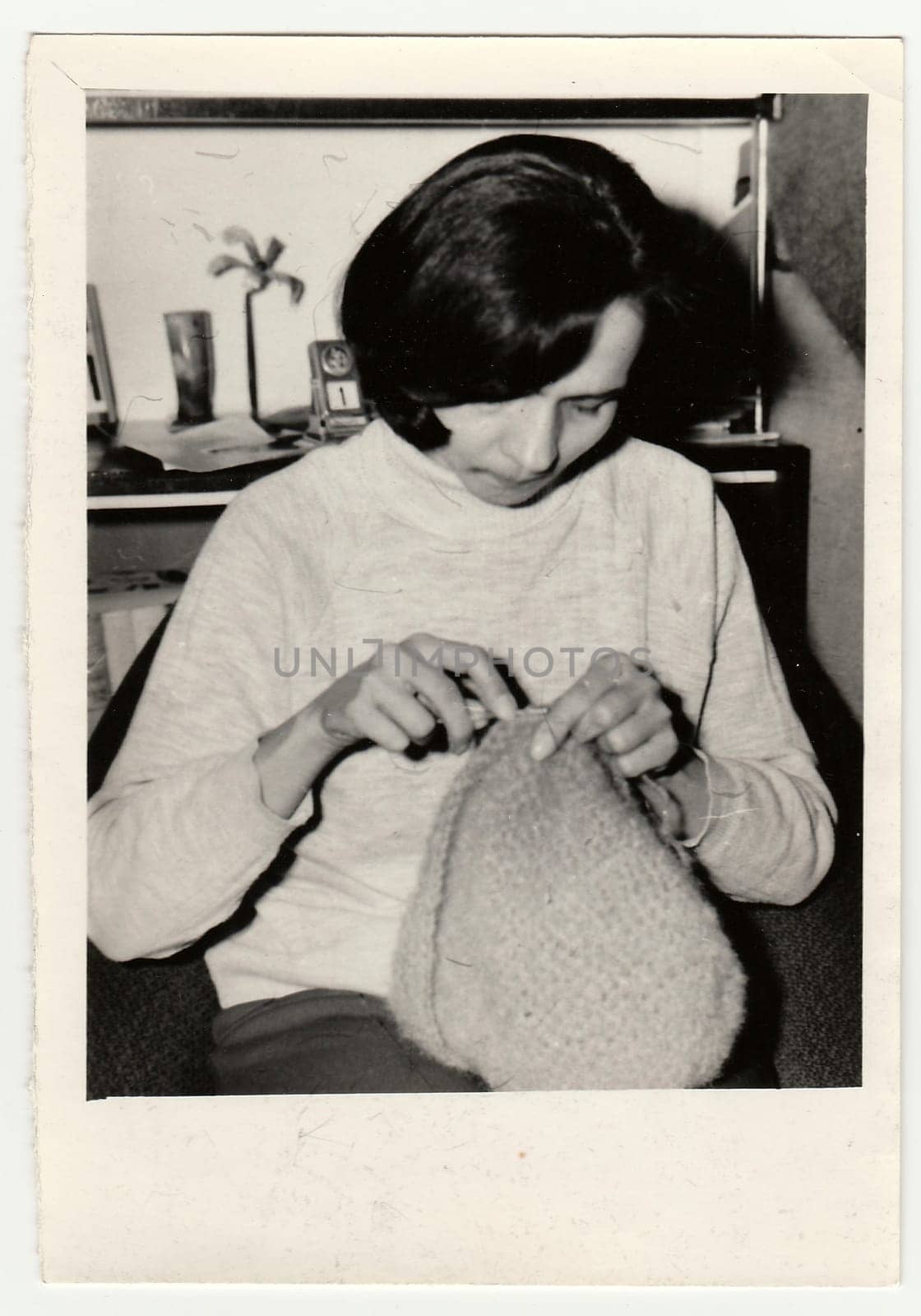 Vintage photo shows woman knits a cap. by roman_nerud