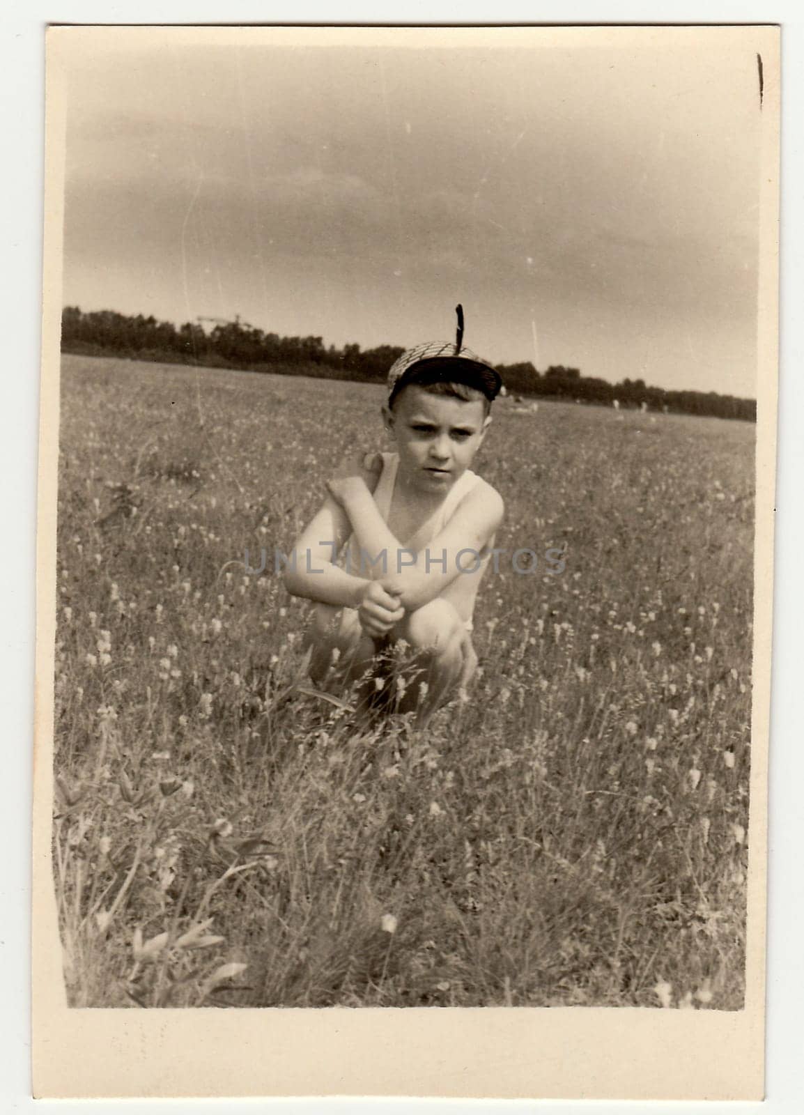 Vintage photo shows boy sits on meadow. by roman_nerud