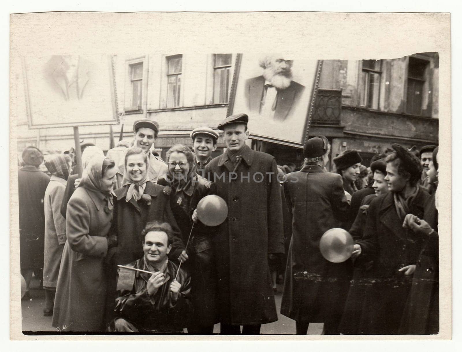 Vintage photo shows people celebrate May Day (International Workers' Day). Picture of Karel Marx on background. by roman_nerud