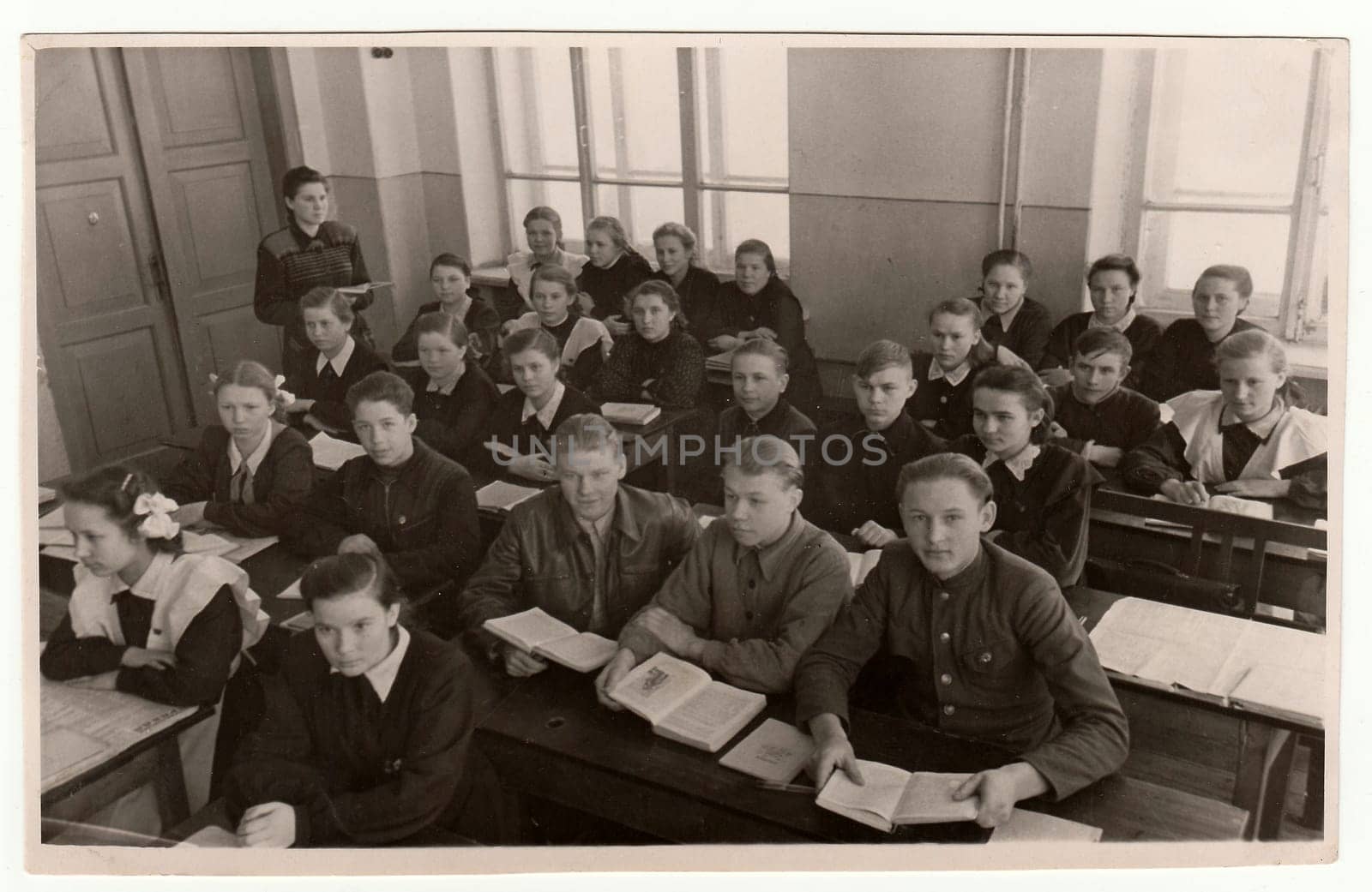 Vintage photo shows schoolmates at school desks. by roman_nerud