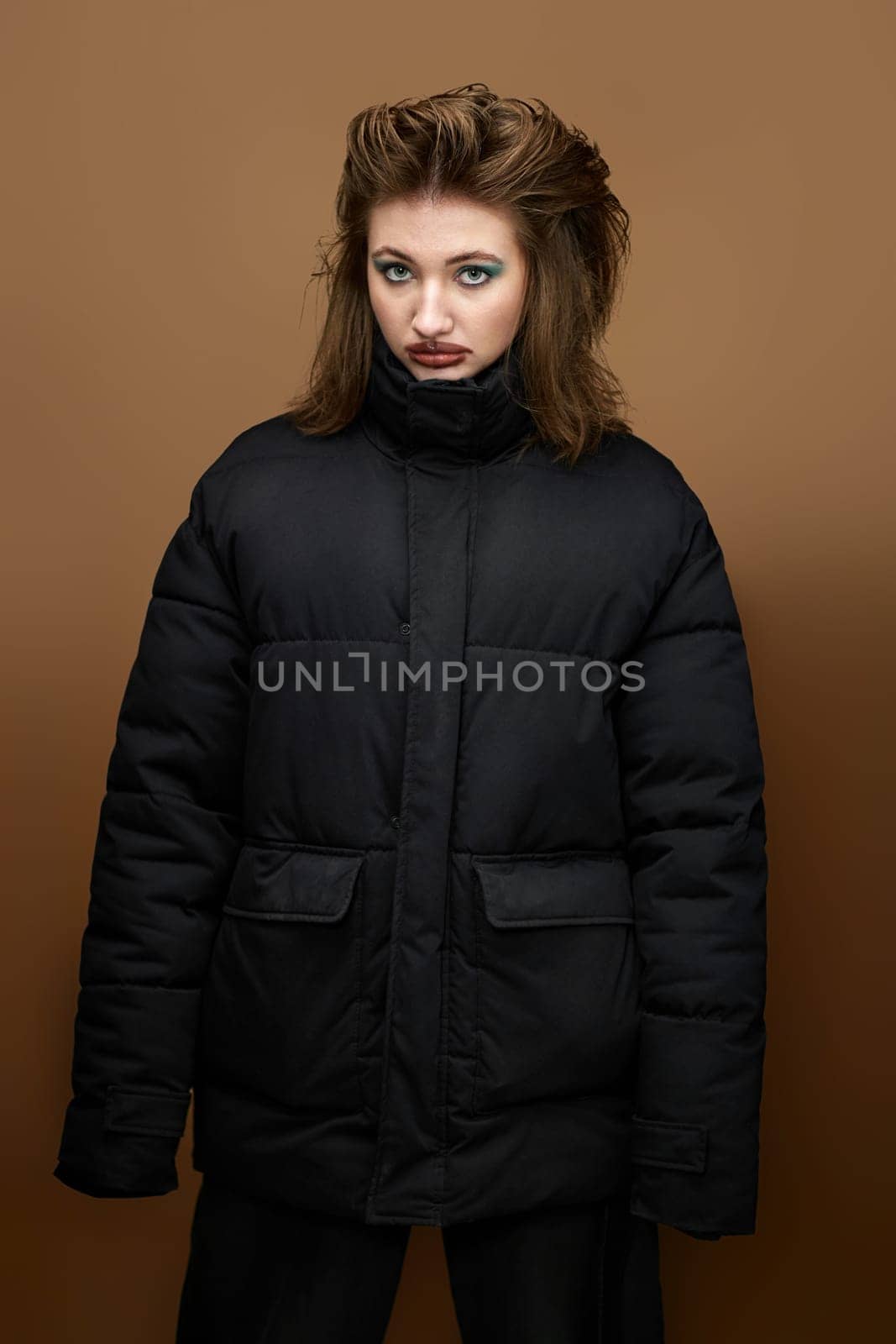 portrait of woman with smudged lipstick and stylish hairstyle in black jacket on beige background.