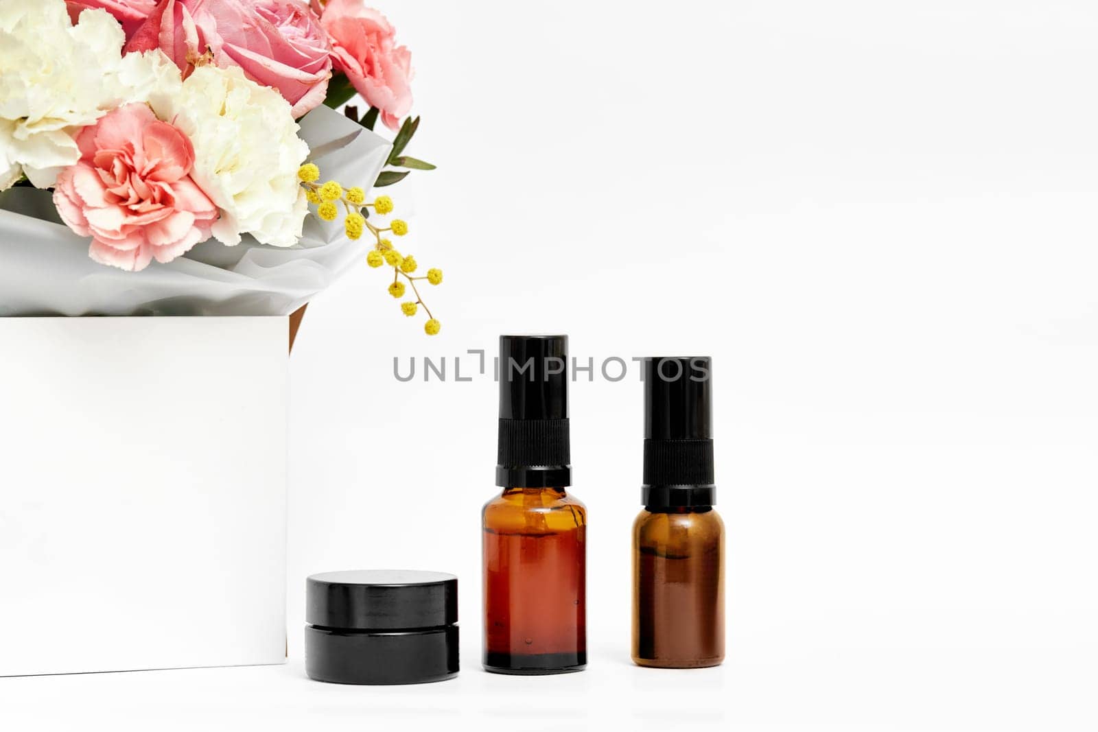 Small glass cosmetic bottle mockup with natural ingredient and flower. natural concept. copy space